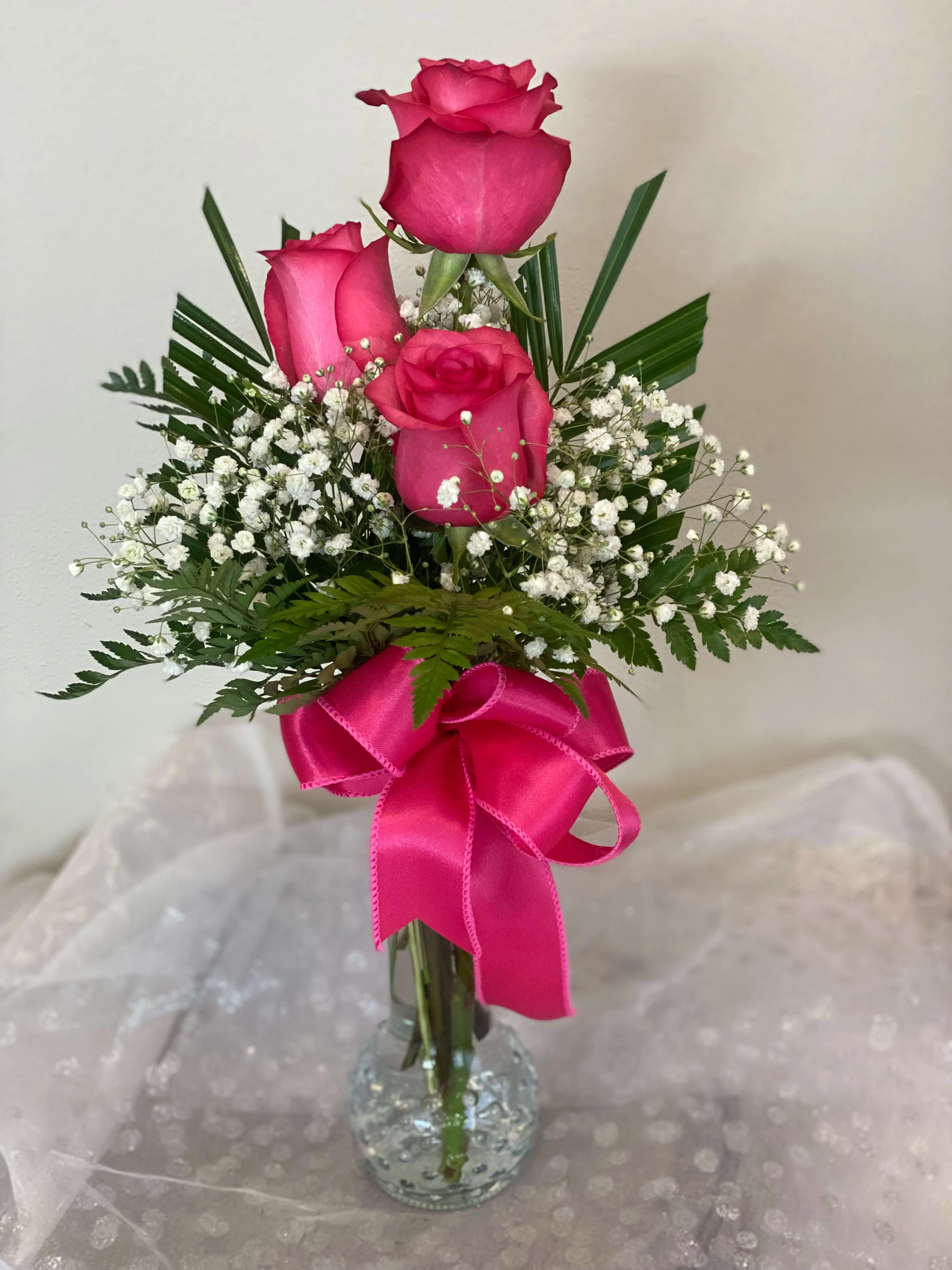 Pink roses in a clear glass vase with a bright ribbon