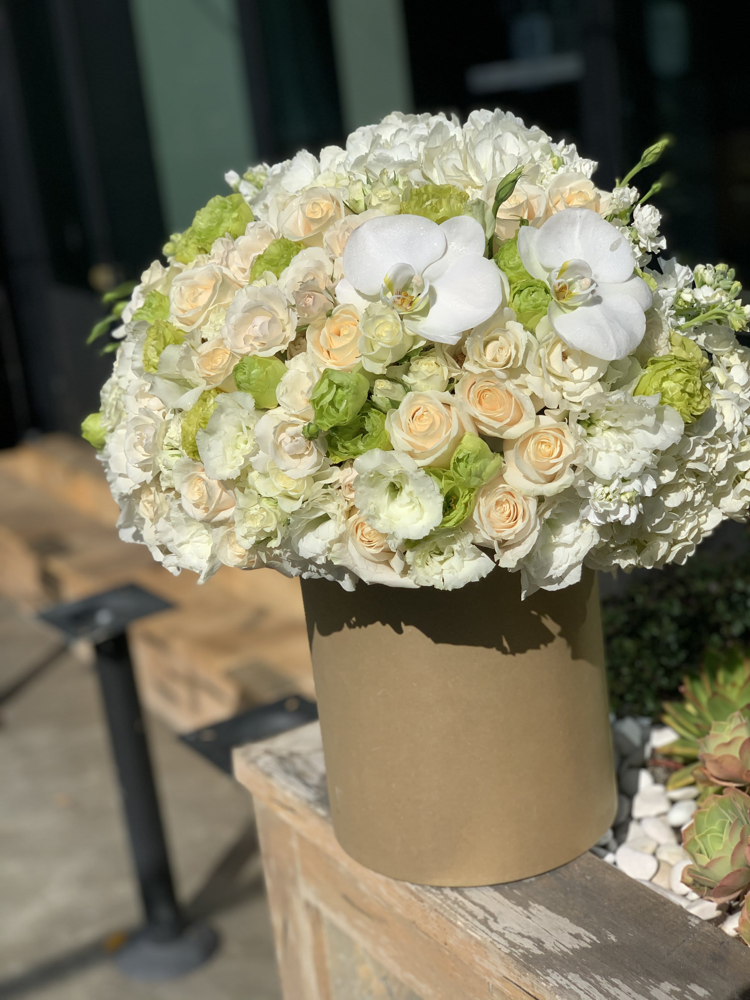 White and cream bouquet with orchids and roses in a tan box