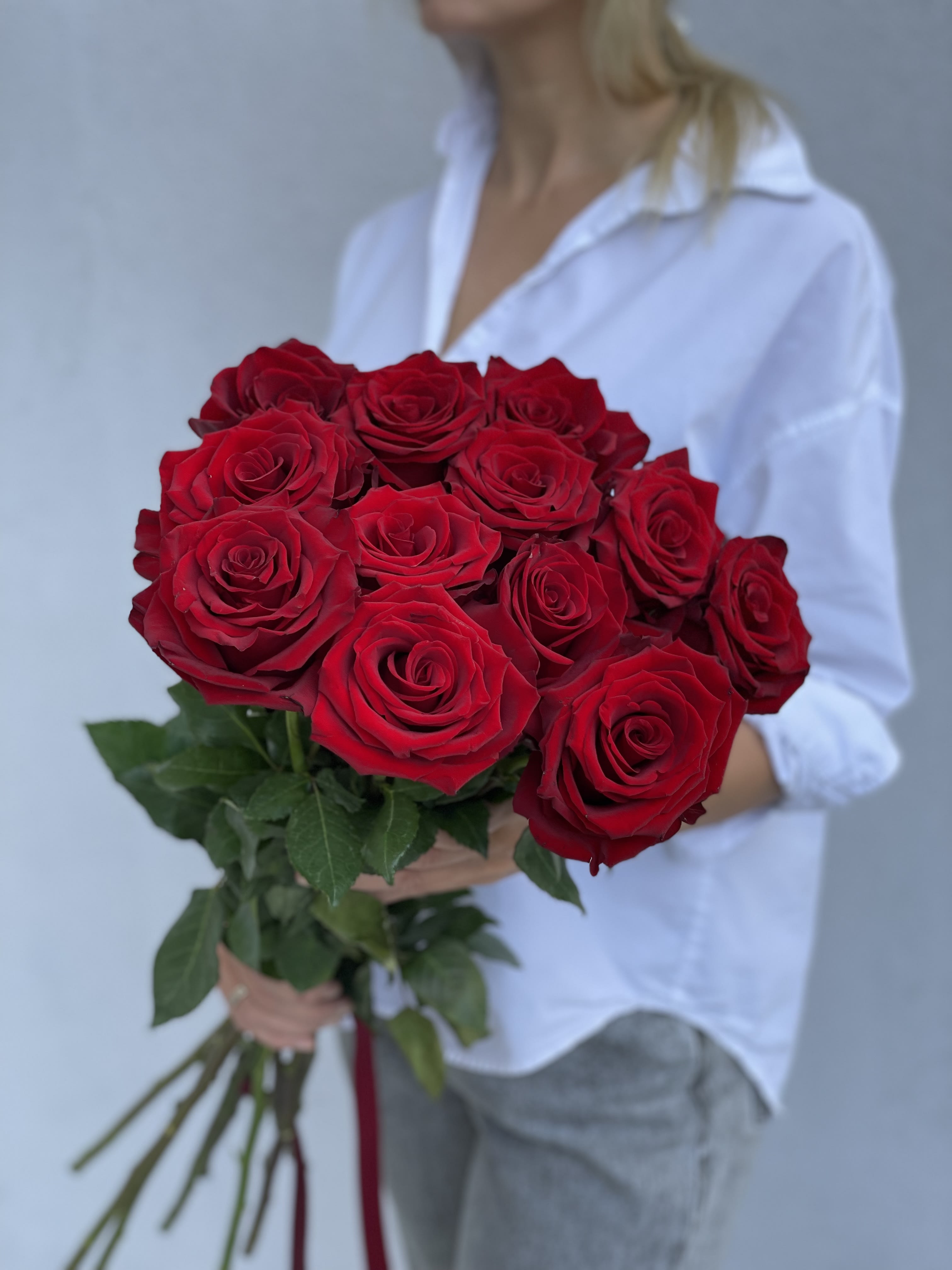 Bouquet of red roses held by a person in a white shirt