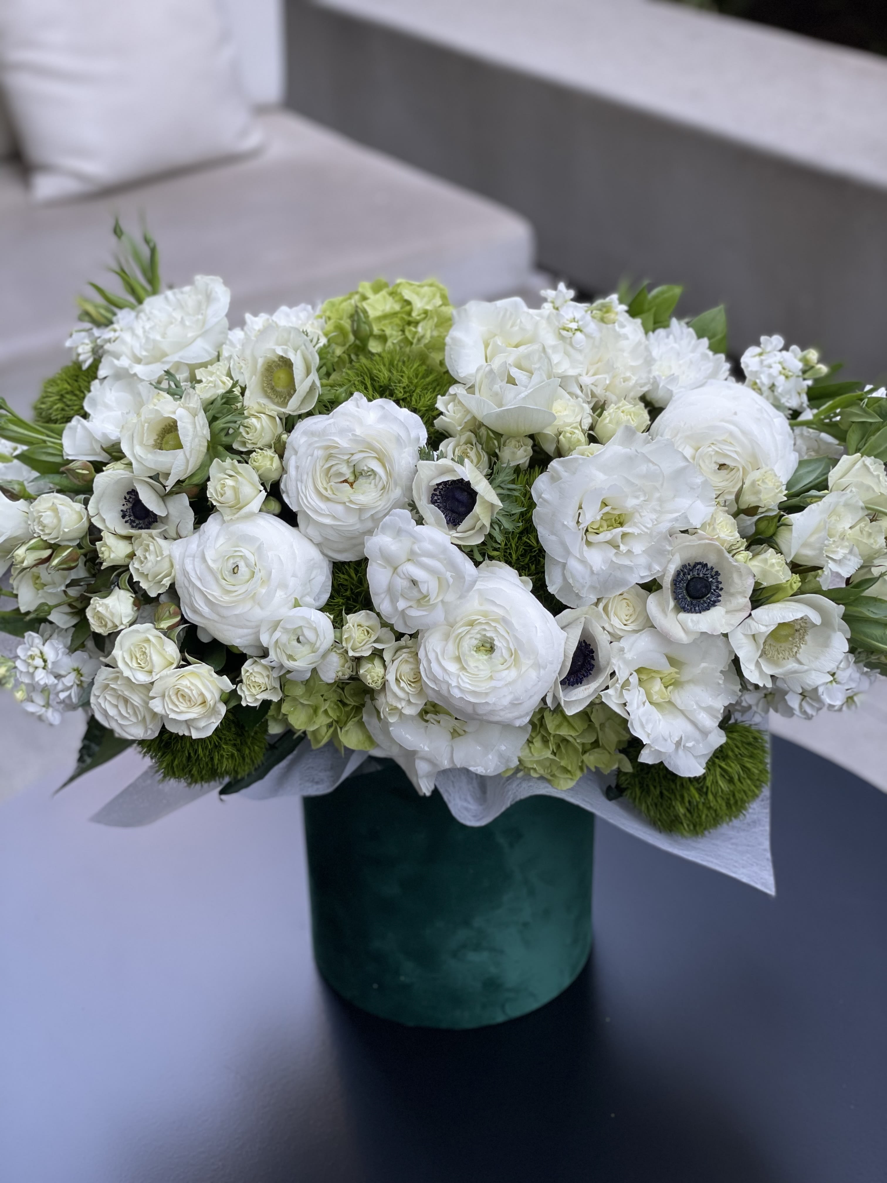 White floral arrangement in a green cylindrical vase