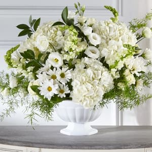 White floral arrangement in a white pedestal vase