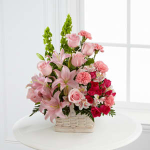 Pink lilies and roses arranged in a wicker basket