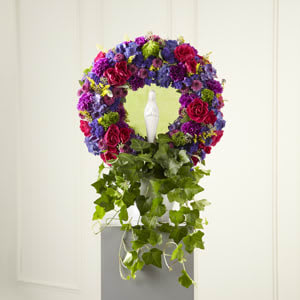 Circular floral wreath with purple, pink, and green flowers on a pedestal