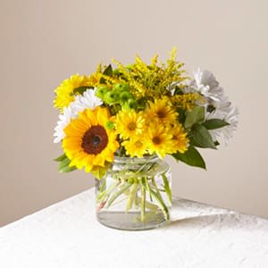 Yellow and white flowers arranged in a clear glass vase