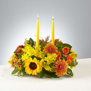 Low floral centerpiece with two yellow taper candles