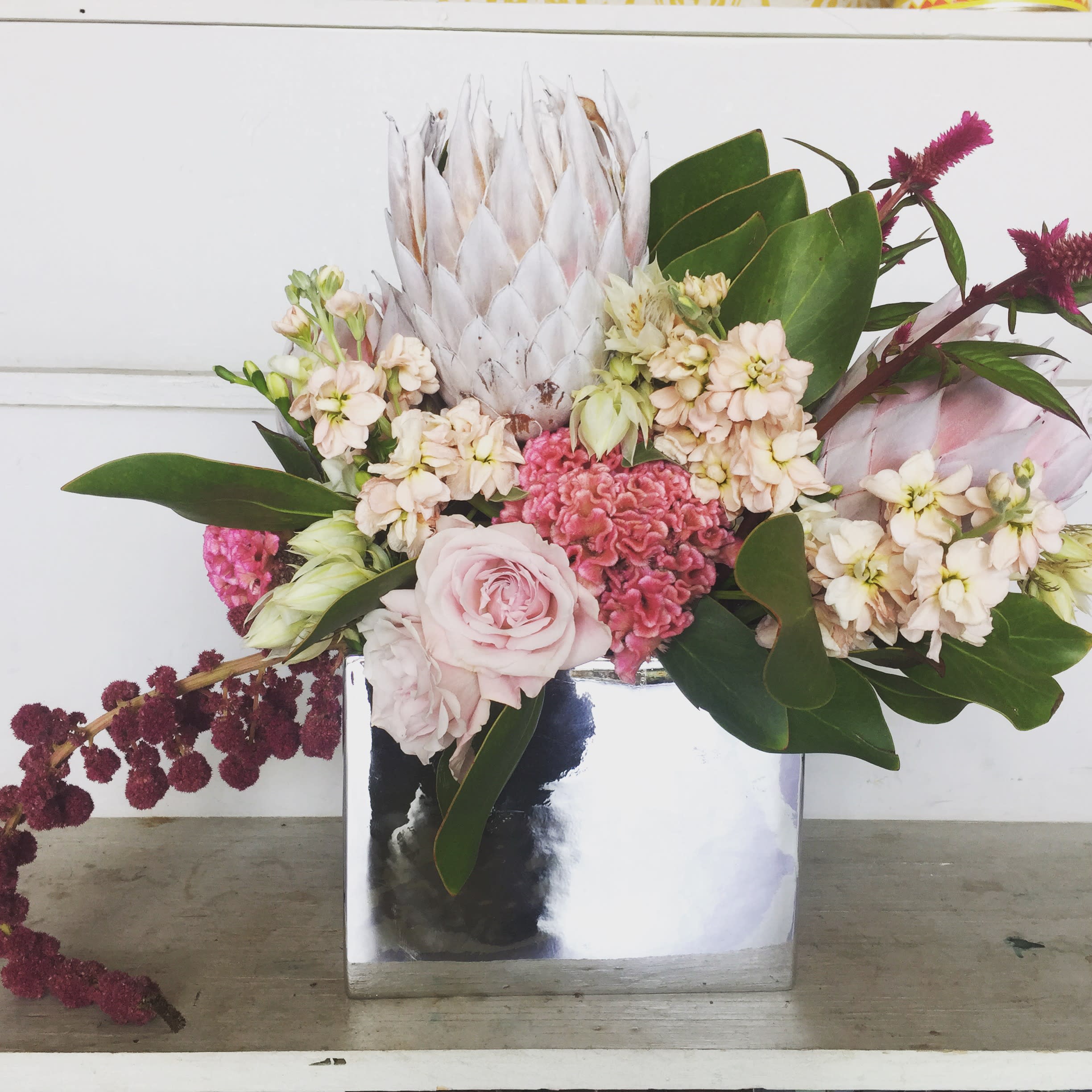 Pink and cream floral arrangement in a mirrored square vase