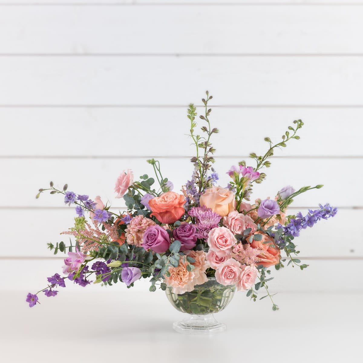 Mixed pink and purple flower arrangement in a clear glass vase