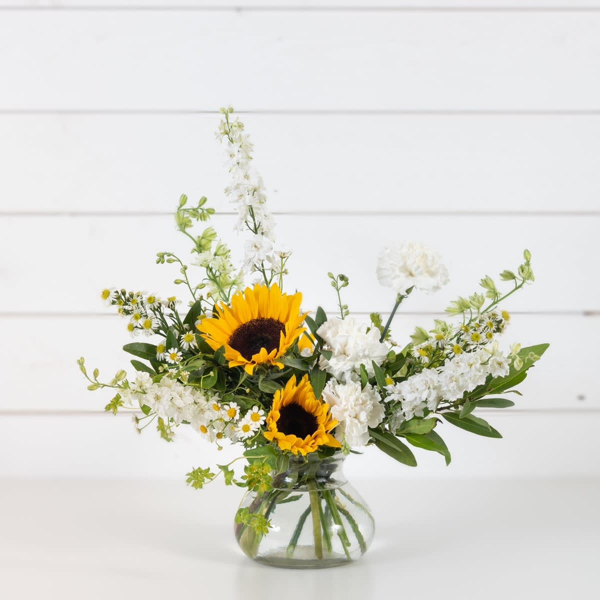 Sunflowers and white flowers in a clear glass vase