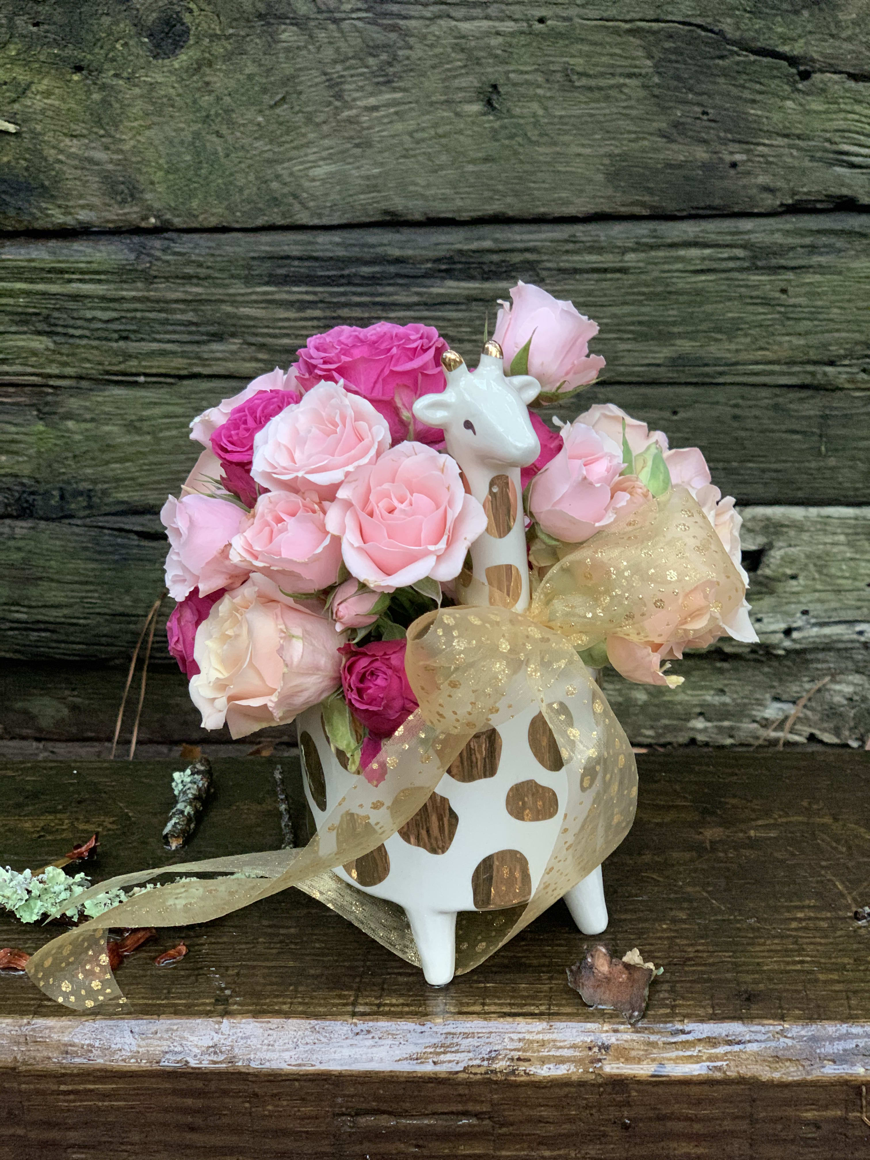 Pink rose bouquet in a giraffe-shaped vase with a gold ribbon