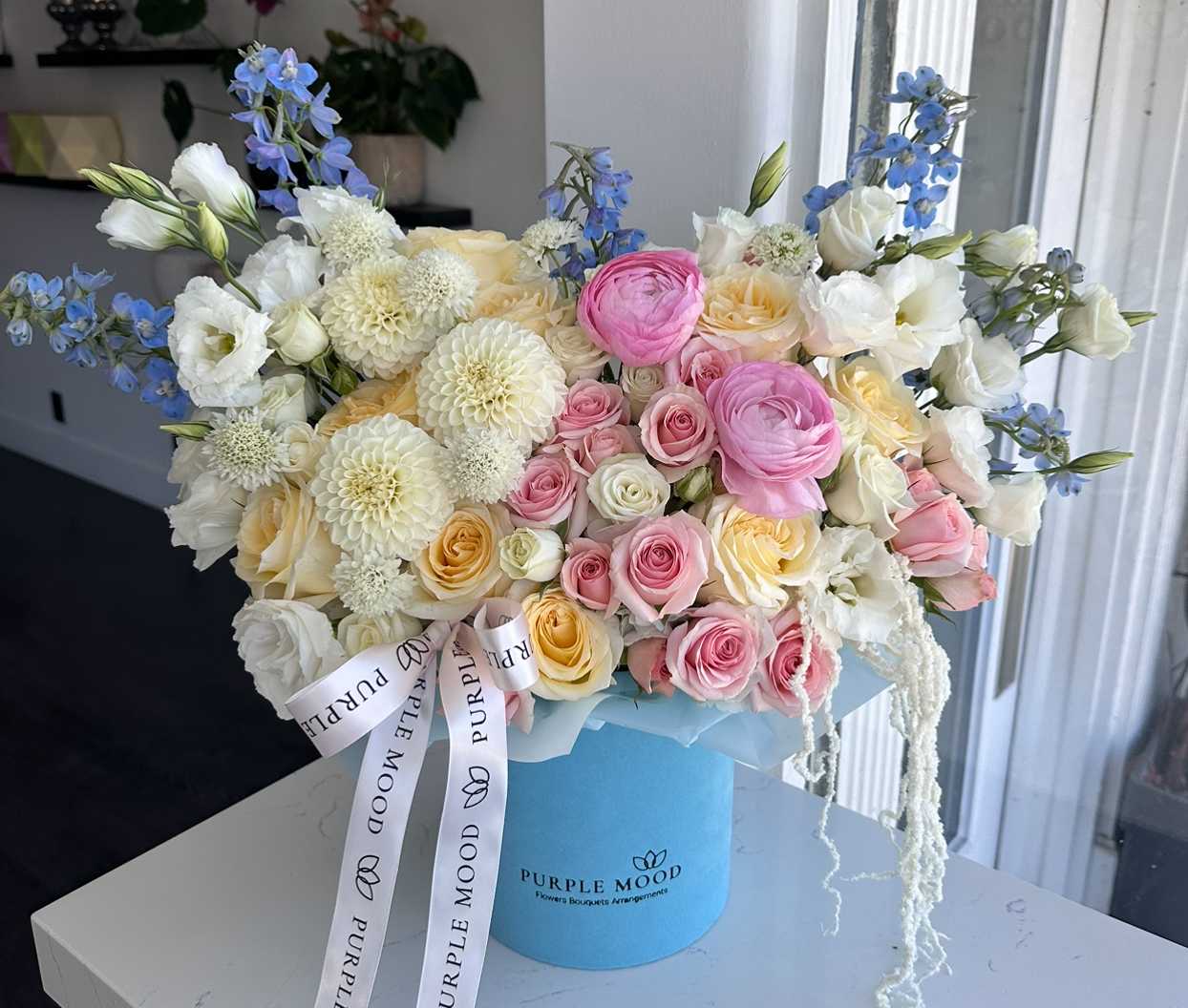 Bouquet of pink, white, and cream flowers in a blue hat box