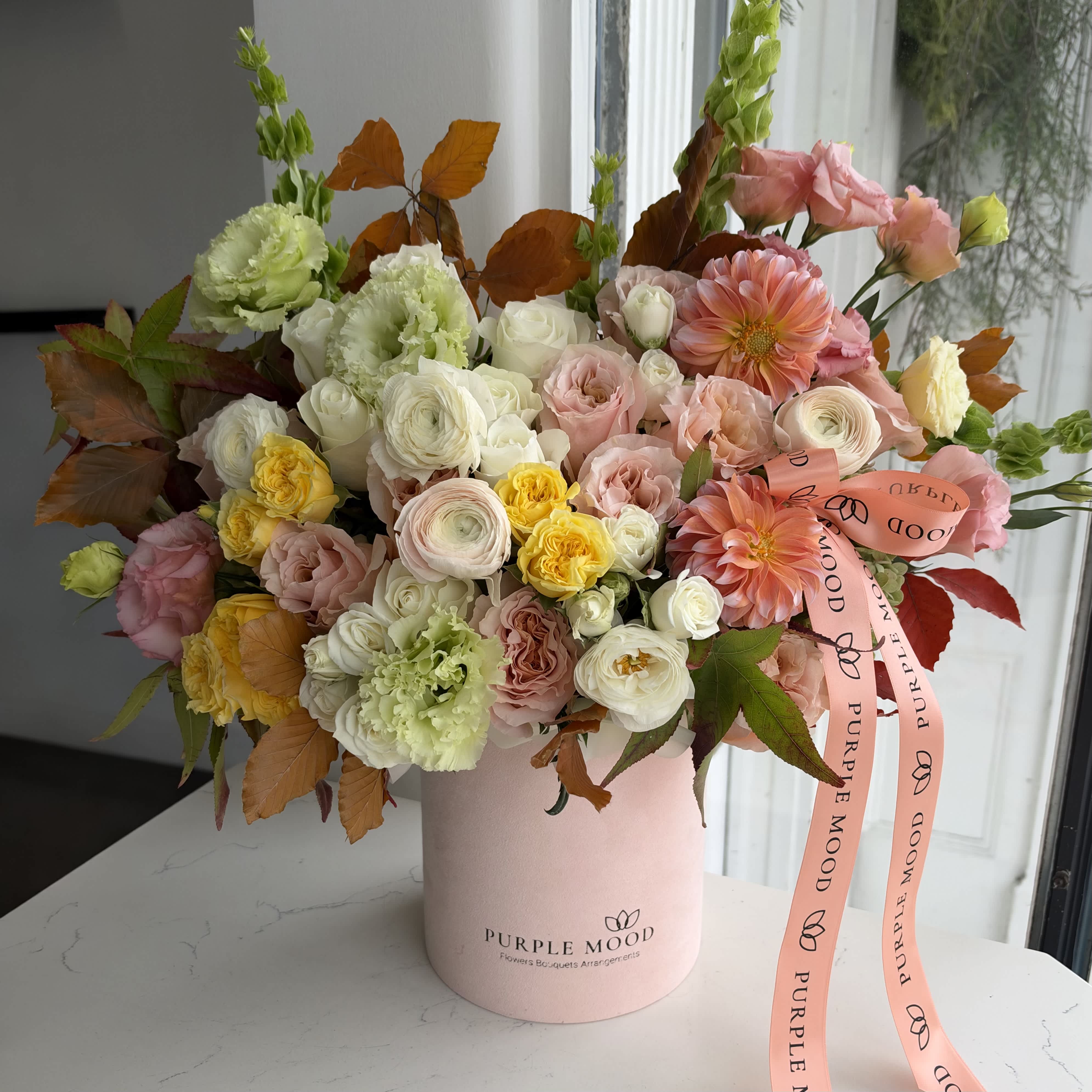 Pastel mixed flower bouquet in a pink hatbox with ribbon