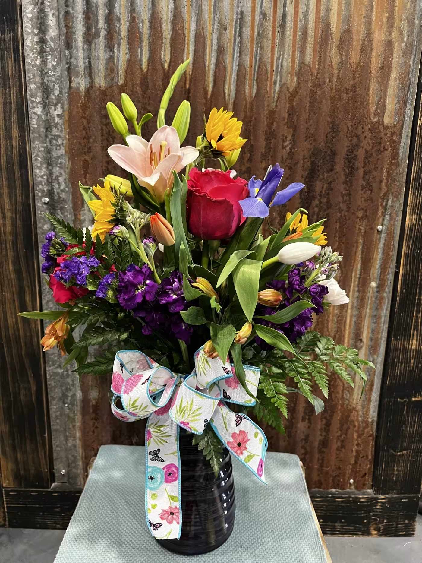 Mixed bouquet in a black vase with a floral ribbon bow