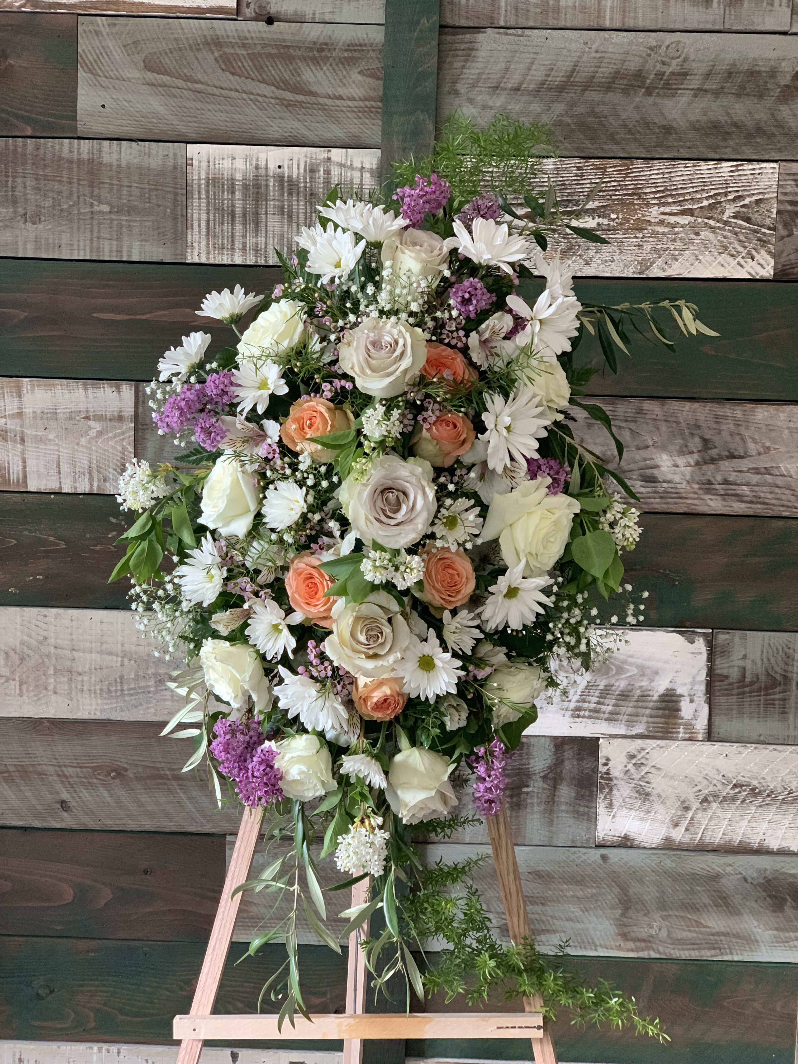 Standing floral spray with white roses, daisies, and purple accents