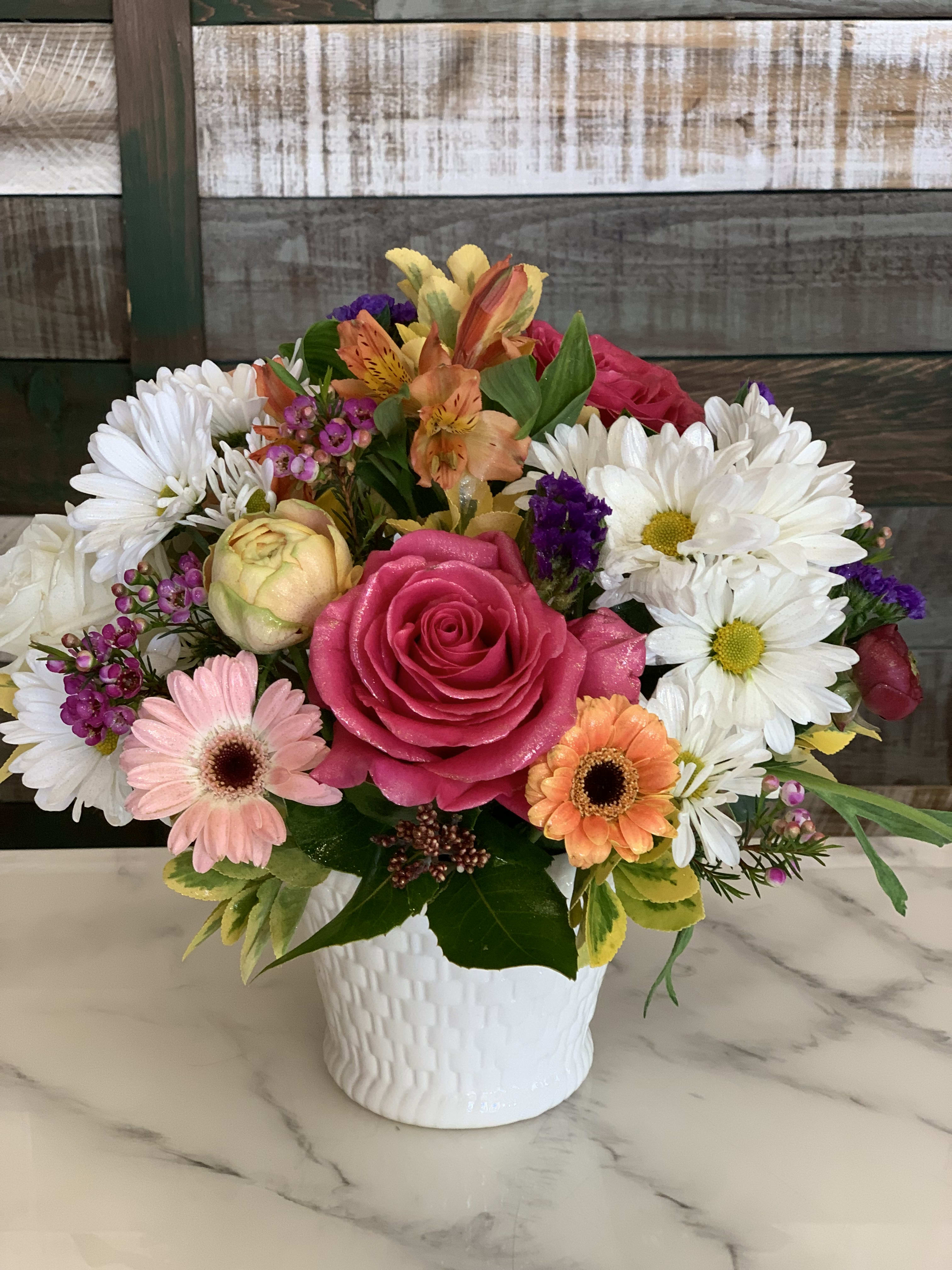 Mixed bouquet with pink roses, daisies, and orange alstroemeria in a white vase