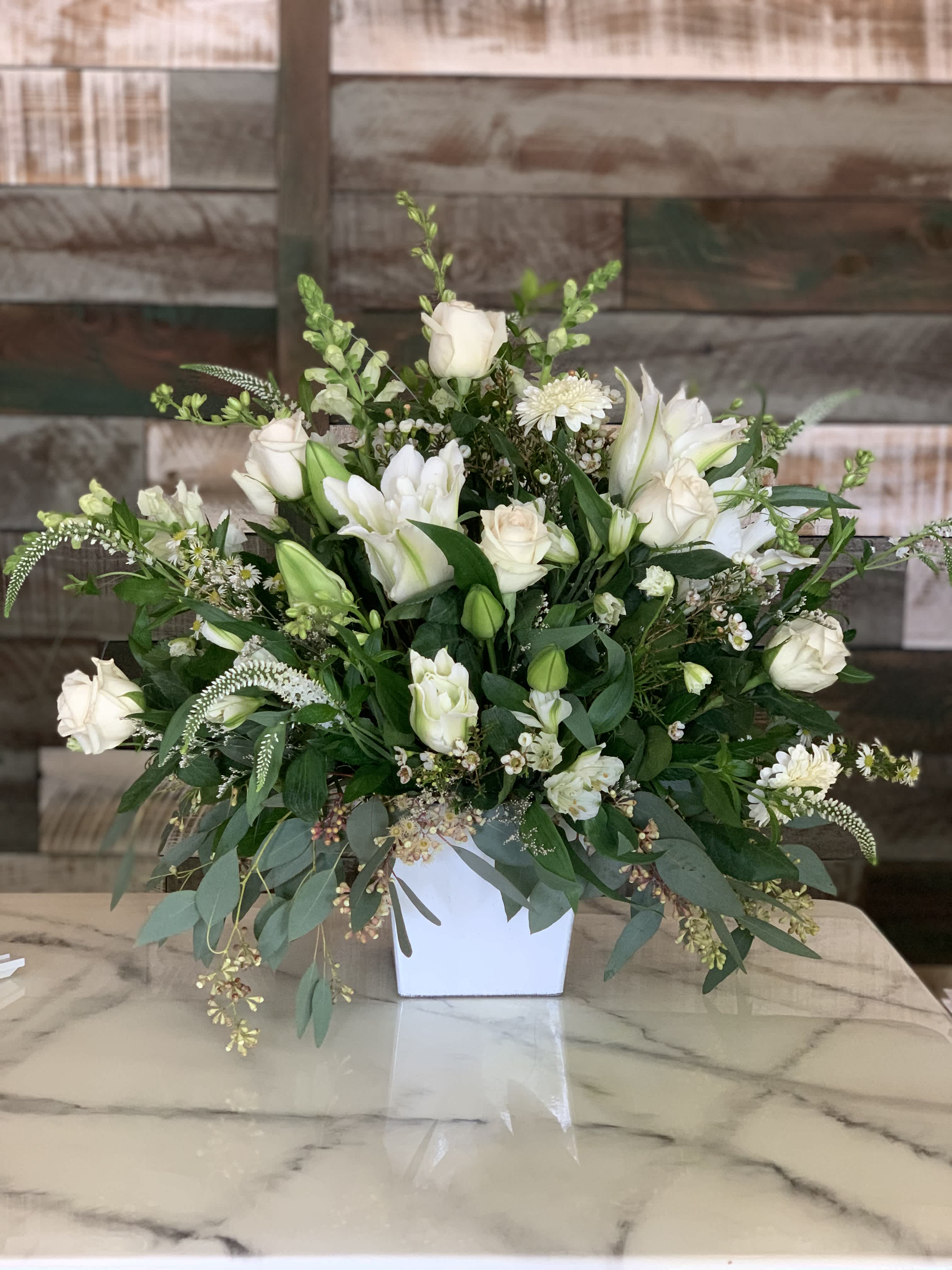 White roses and lilies arranged in a white vase