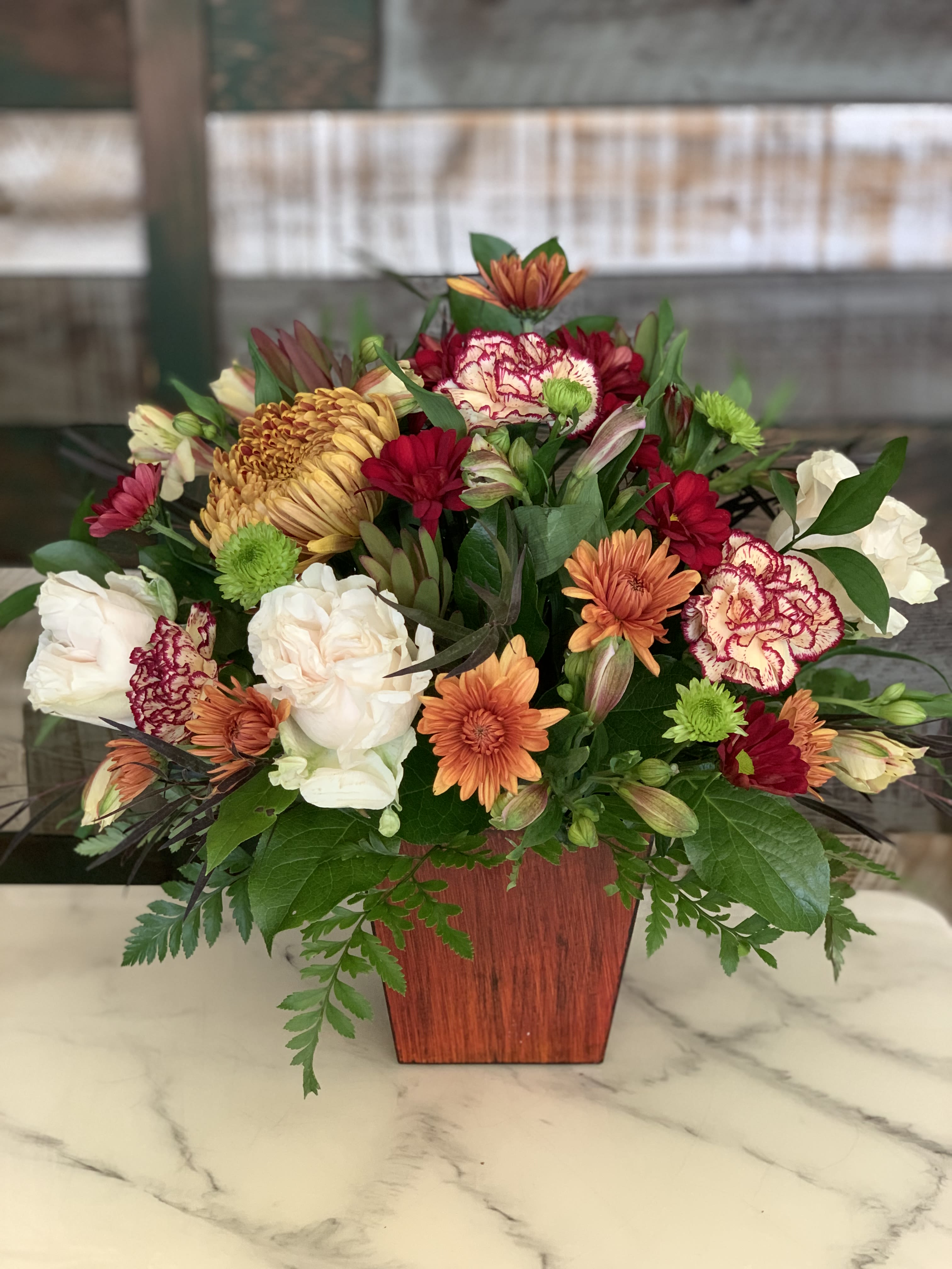 Mixed bouquet of chrysanthemums and carnations in a wooden vase