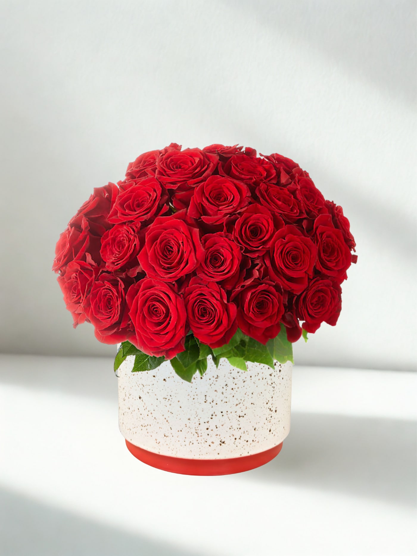 Red roses arranged in a round white speckled vase