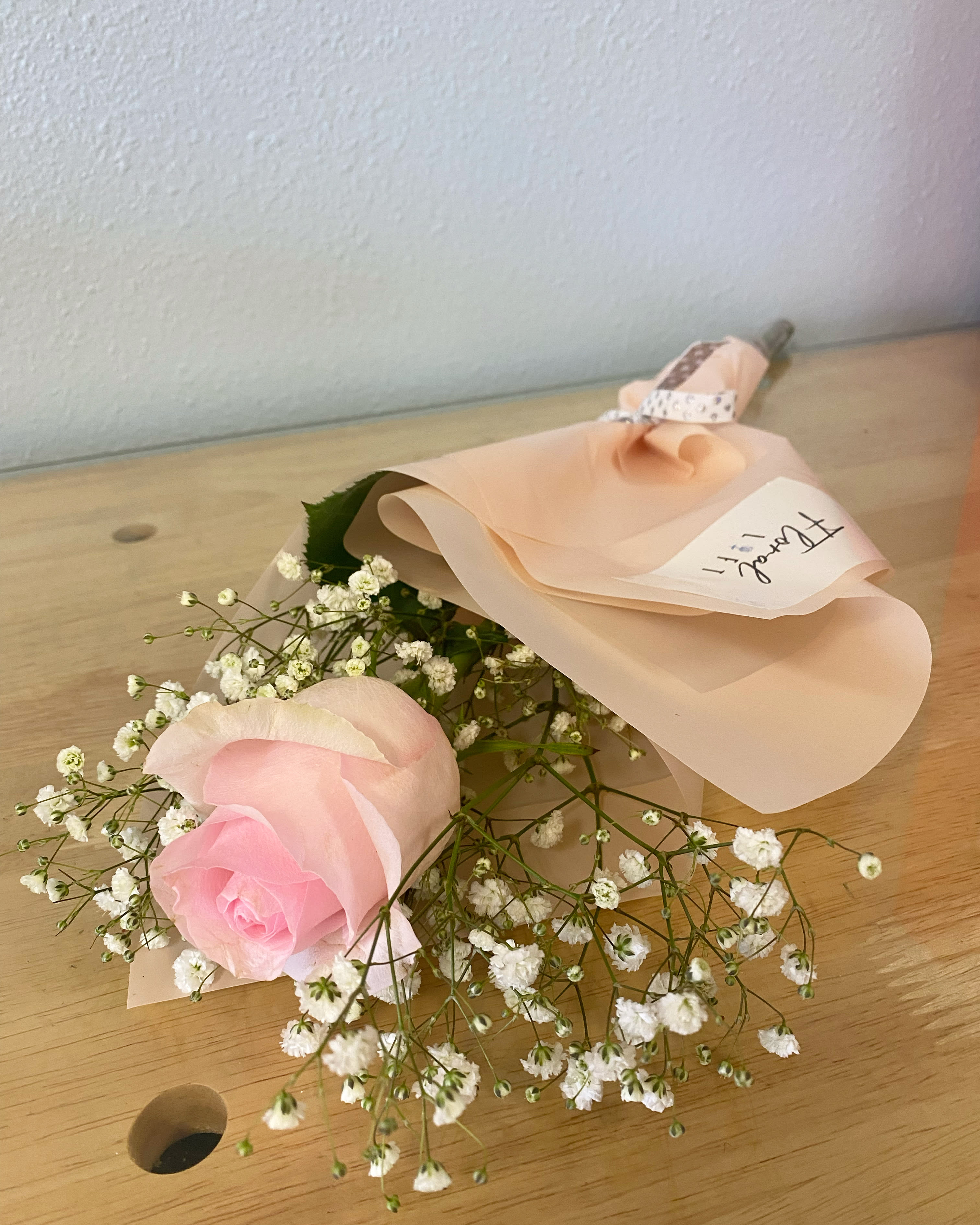 Single pink rose bouquet with baby's breath wrapped in pale peach paper