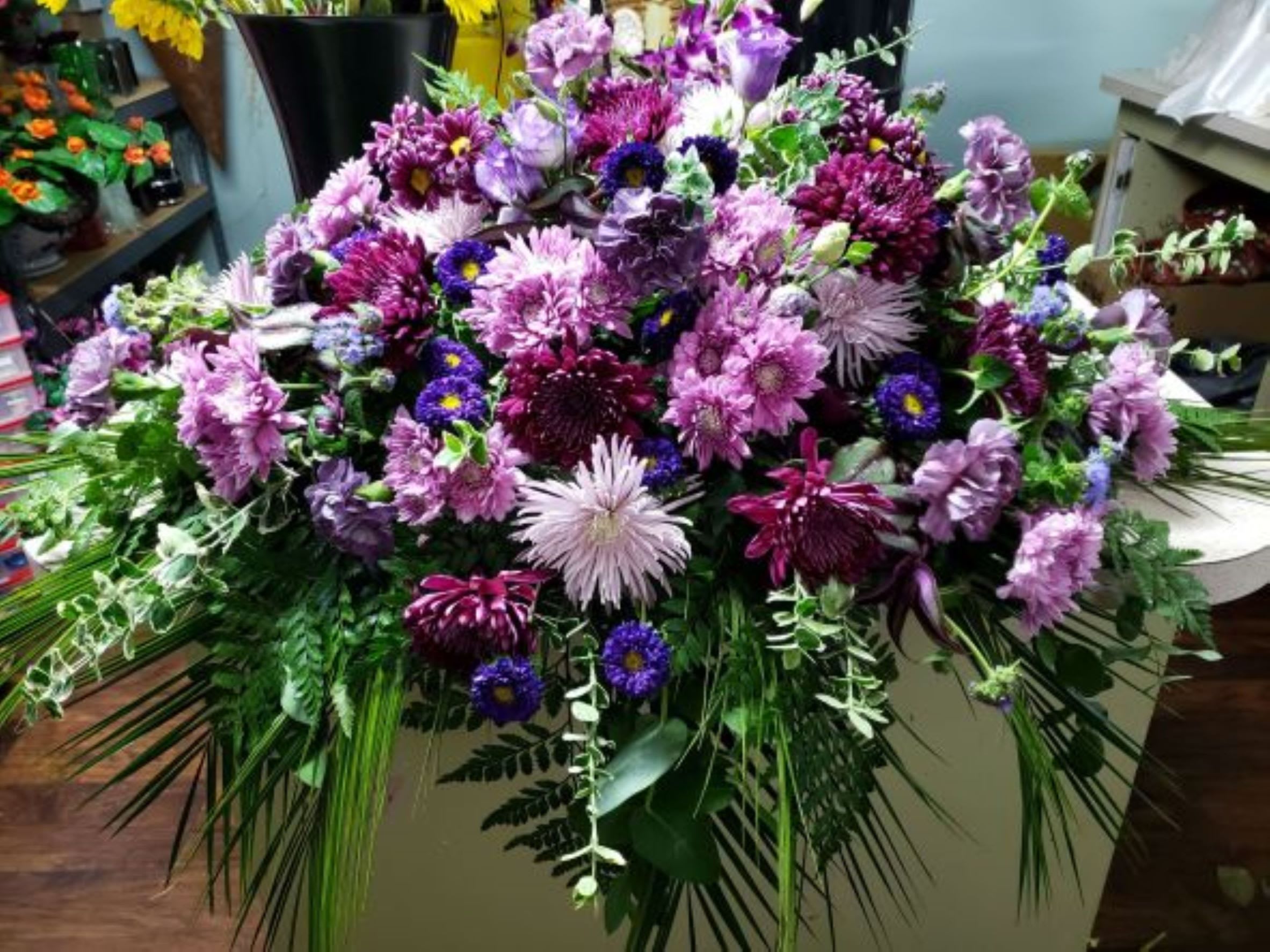 Large purple and lavender floral arrangement with cascading greenery