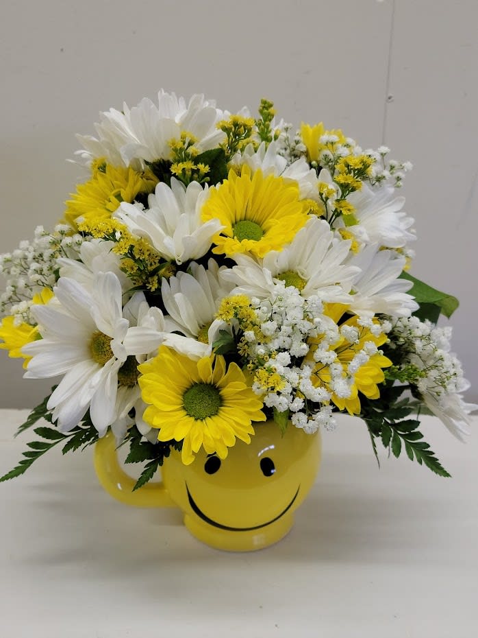 Yellow and white daisy bouquet in a smiley-face mug