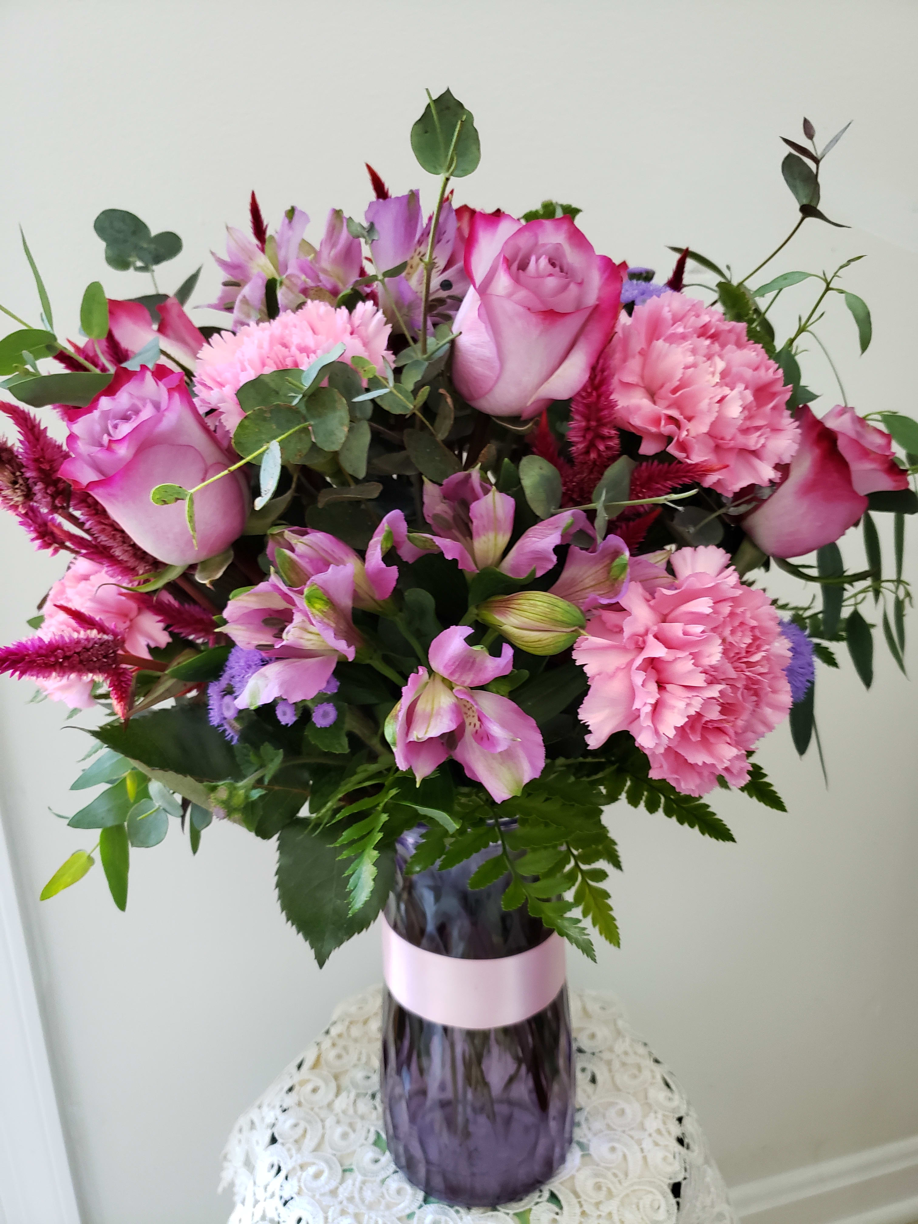 Pink roses and carnations in a purple glass vase