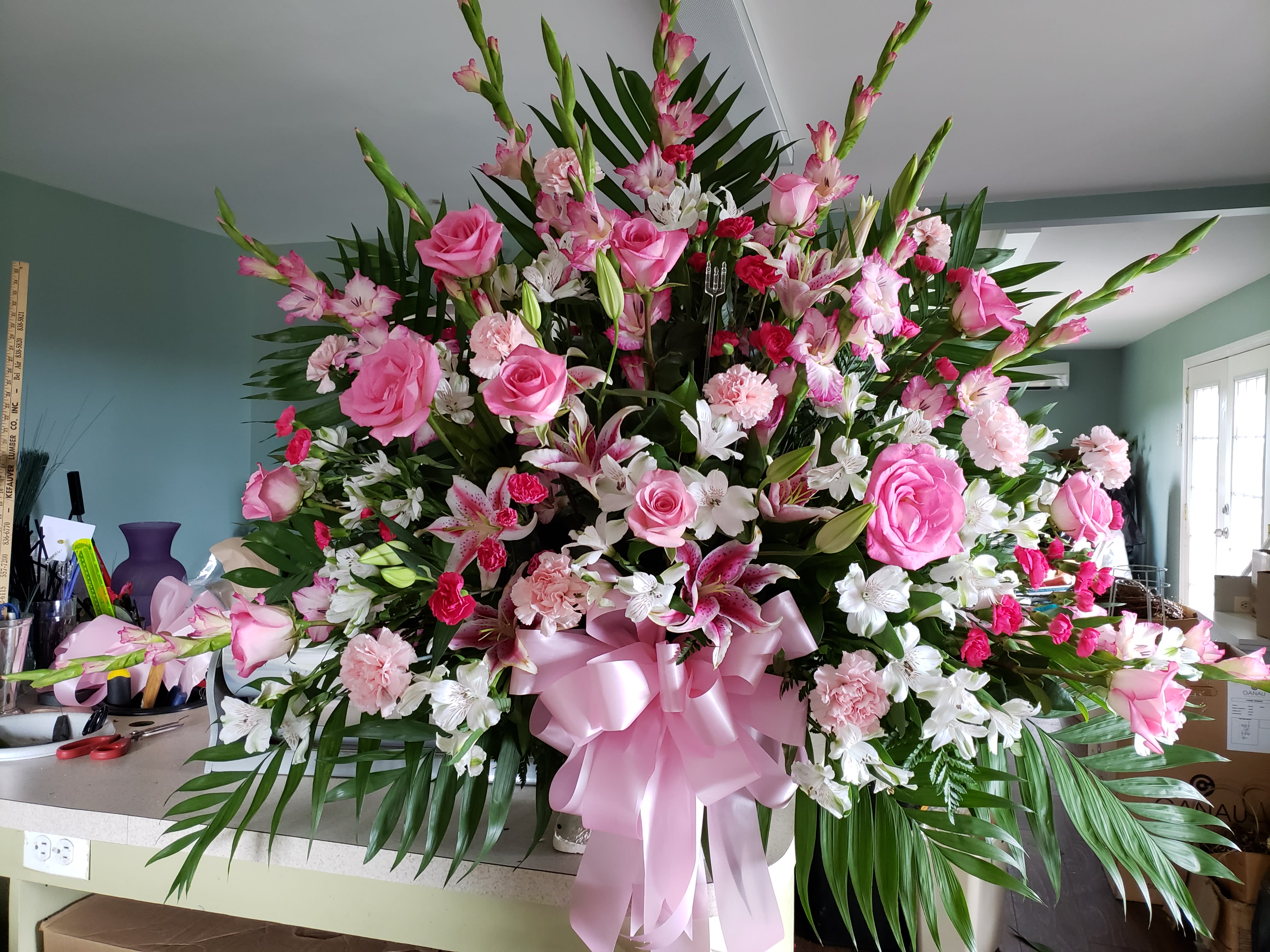 Large pink and white floral arrangement with a pink ribbon bow