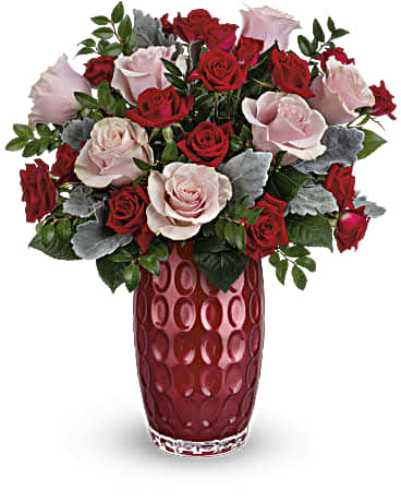 Red and pale pink roses arranged in a tall red vase