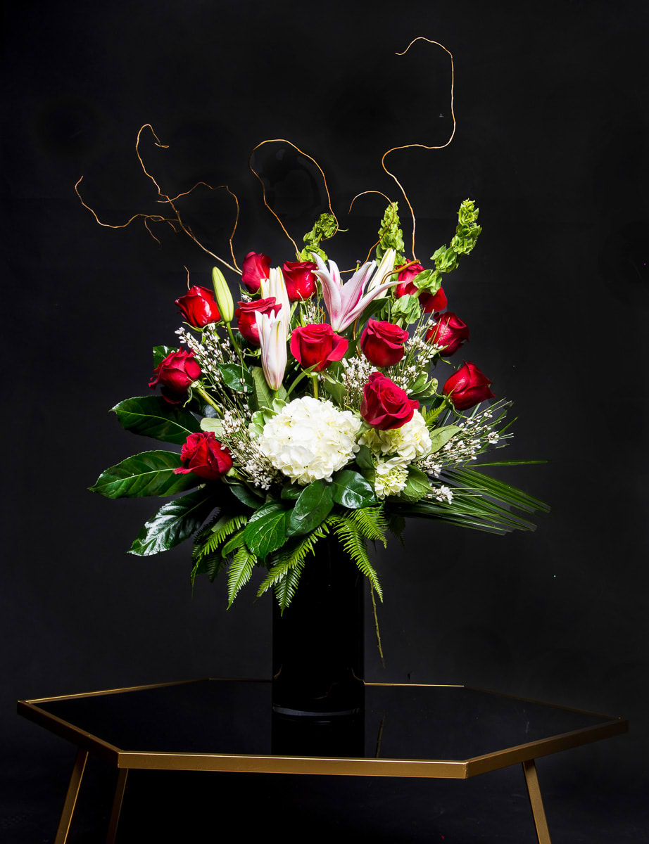 Red roses and white lilies arranged in a tall black vase