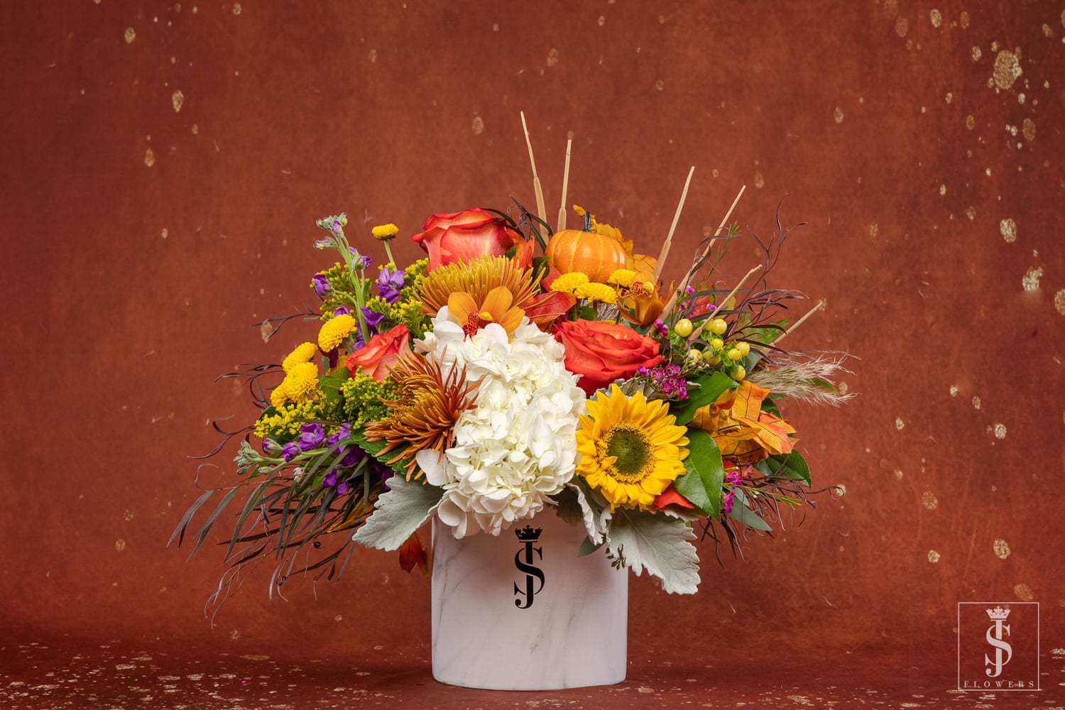 Mixed autumn bouquet in a white vase with sunflowers, roses, and hydrangea