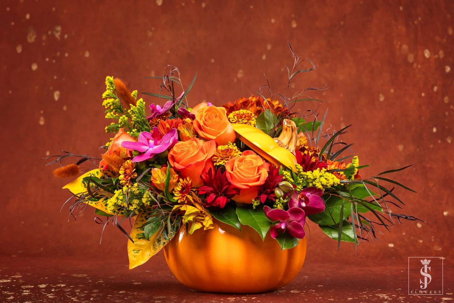 Orange and magenta floral arrangement in a pumpkin-shaped vase