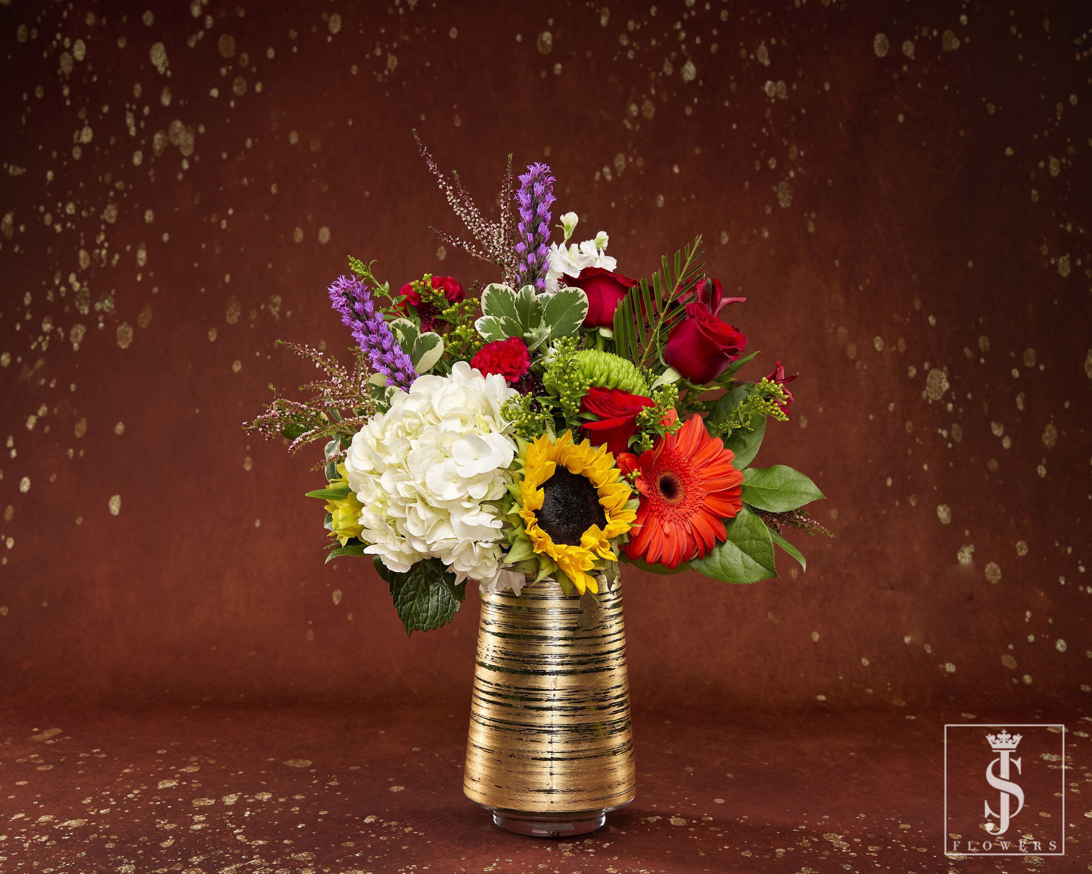 Mixed bouquet in a gold striped vase with red, white, and orange flowers