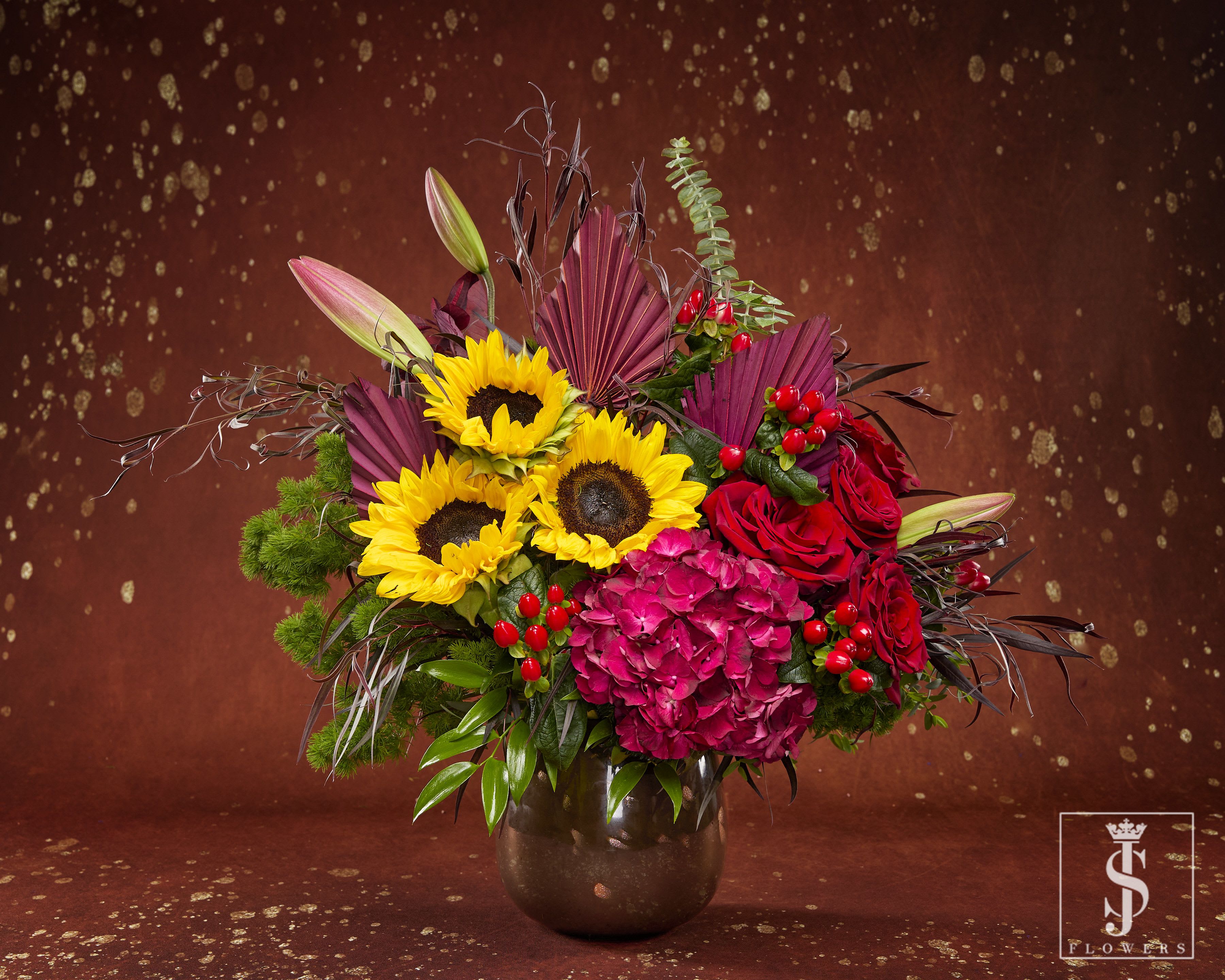 Bouquet of sunflowers, red roses, and pink hydrangea in a dark vase
