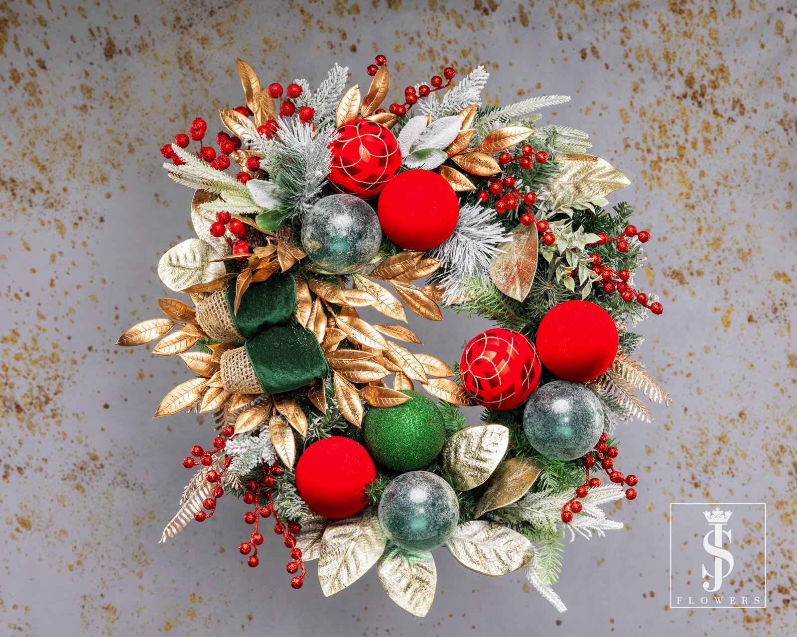 Gilded Christmas Wreath - The Gilded Christmas Wreath is a breathtaking centerpiece for your holiday décor. Featuring metallic gold leaves, vibrant red berries, and shimmering baubles, it perfectly captures the spirit of Christmas. Frosted evergreen branches add a wintry charm, while the luxurious velvet green ribbon enhances its festive sophistication. Handcrafted with care, this wreath is designed to bring timeless beauty to your home. Whether hung on your door, wall, or mantel, it creates a warm and inviting atmosphere for the holiday season. Celebrate Christmas in style with this exquisite blend of elegance and cheer.