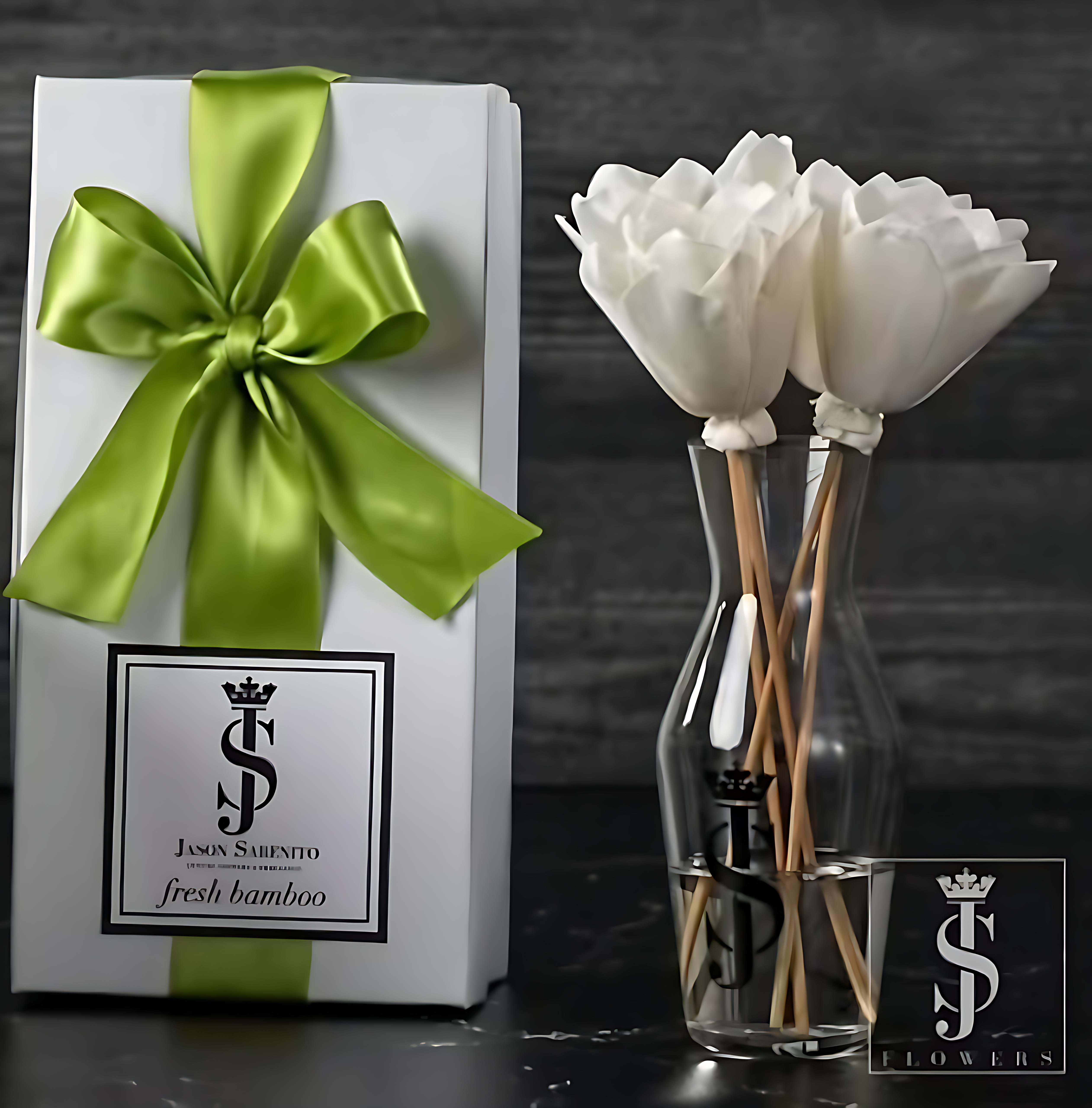 White flowers in a clear vase beside a gift box with a green ribbon