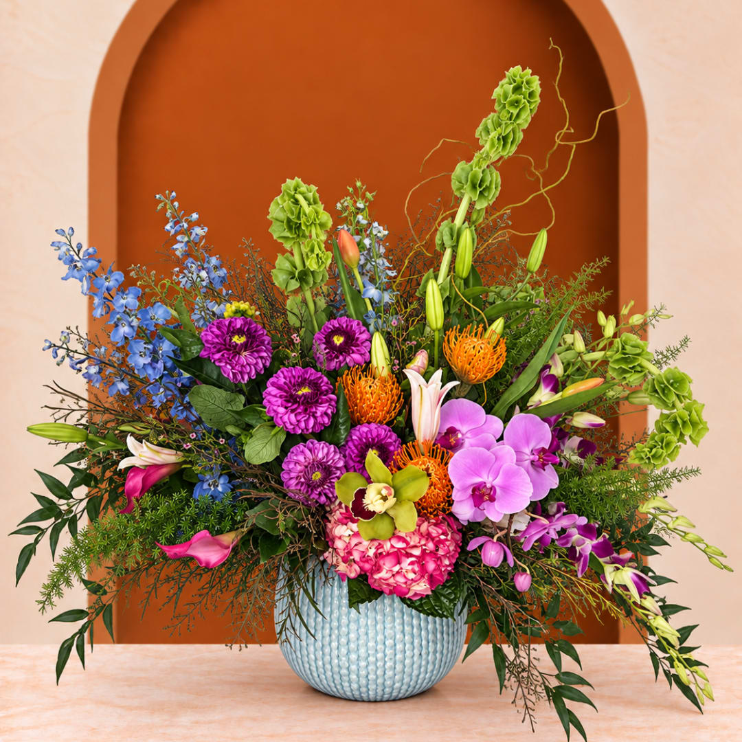 Colorful mixed flower arrangement in a light blue textured vase