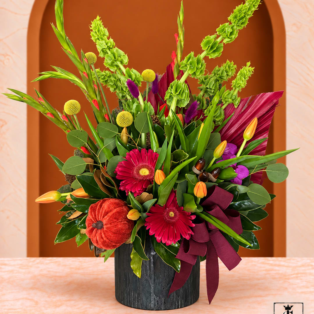 Tropical floral arrangement in a black vase with a burgundy ribbon