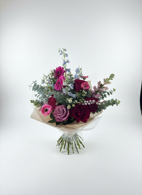 Bouquet of pink, purple, and blue flowers wrapped in beige paper
