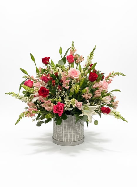 Mixed pink and red flower arrangement in a gray vase
