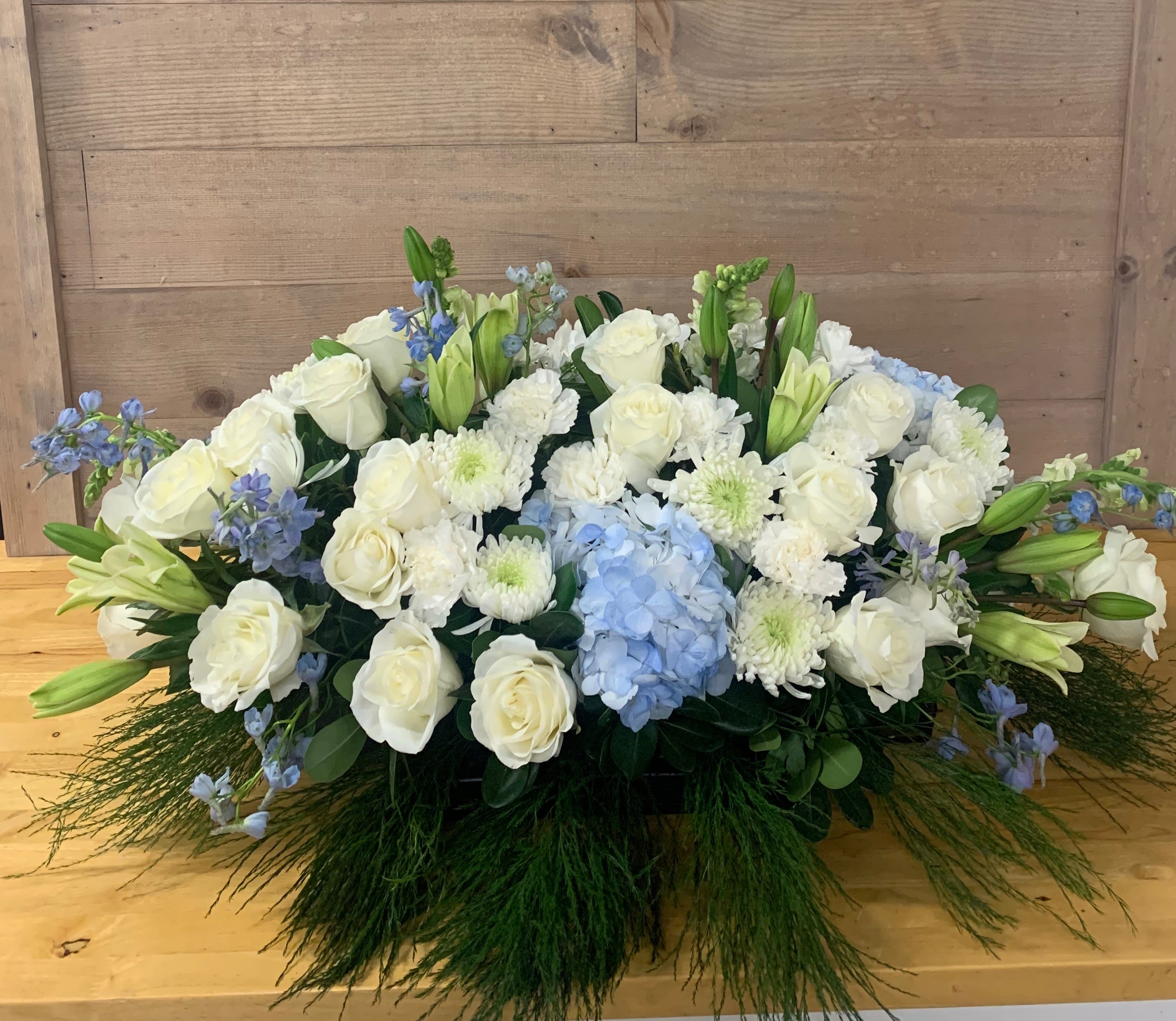 Low floral arrangement of white roses, lilies, and blue hydrangea