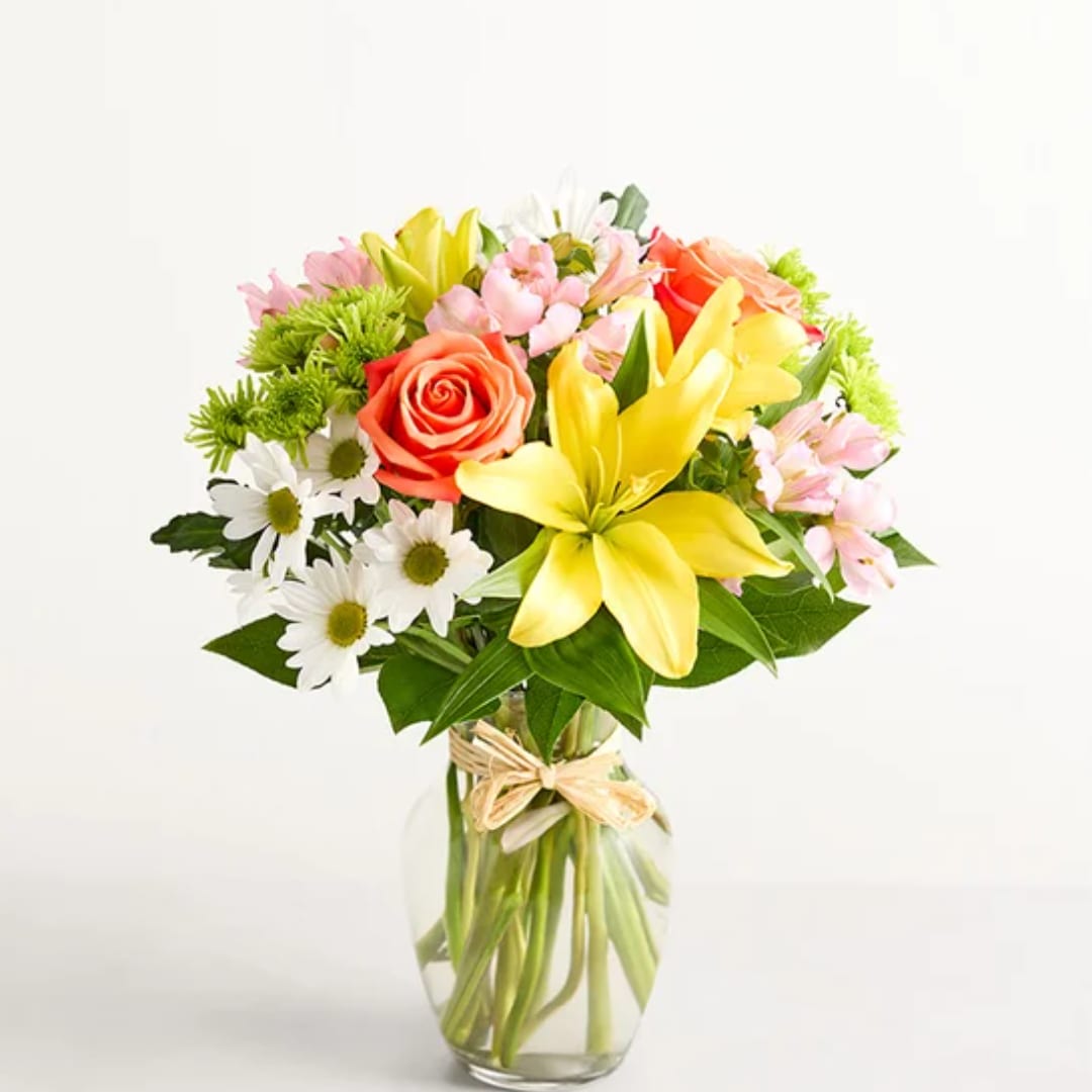 Mixed bouquet of lilies, roses, and daisies in a glass vase