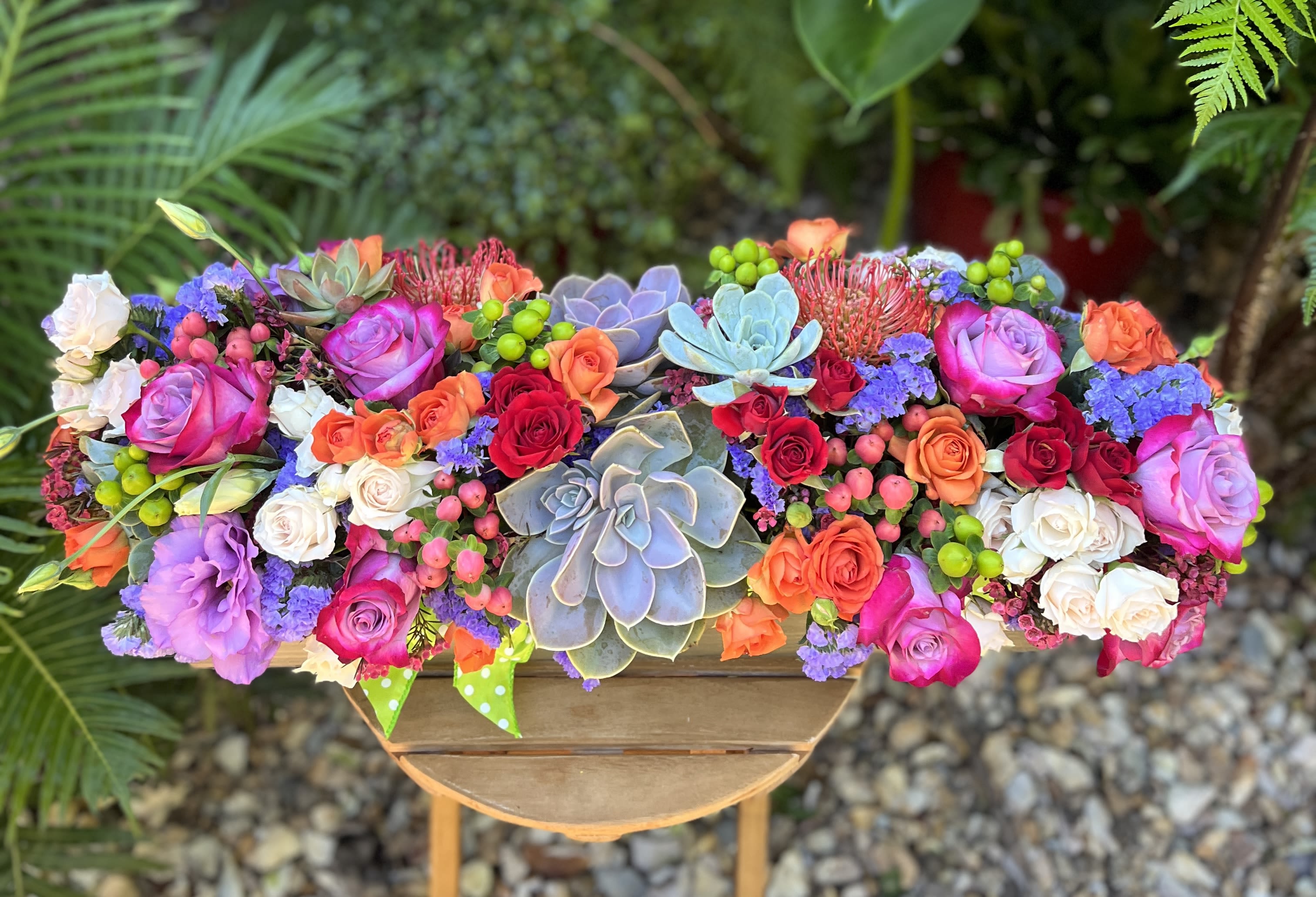 Colorful floral arrangement with roses and succulents in a wooden container