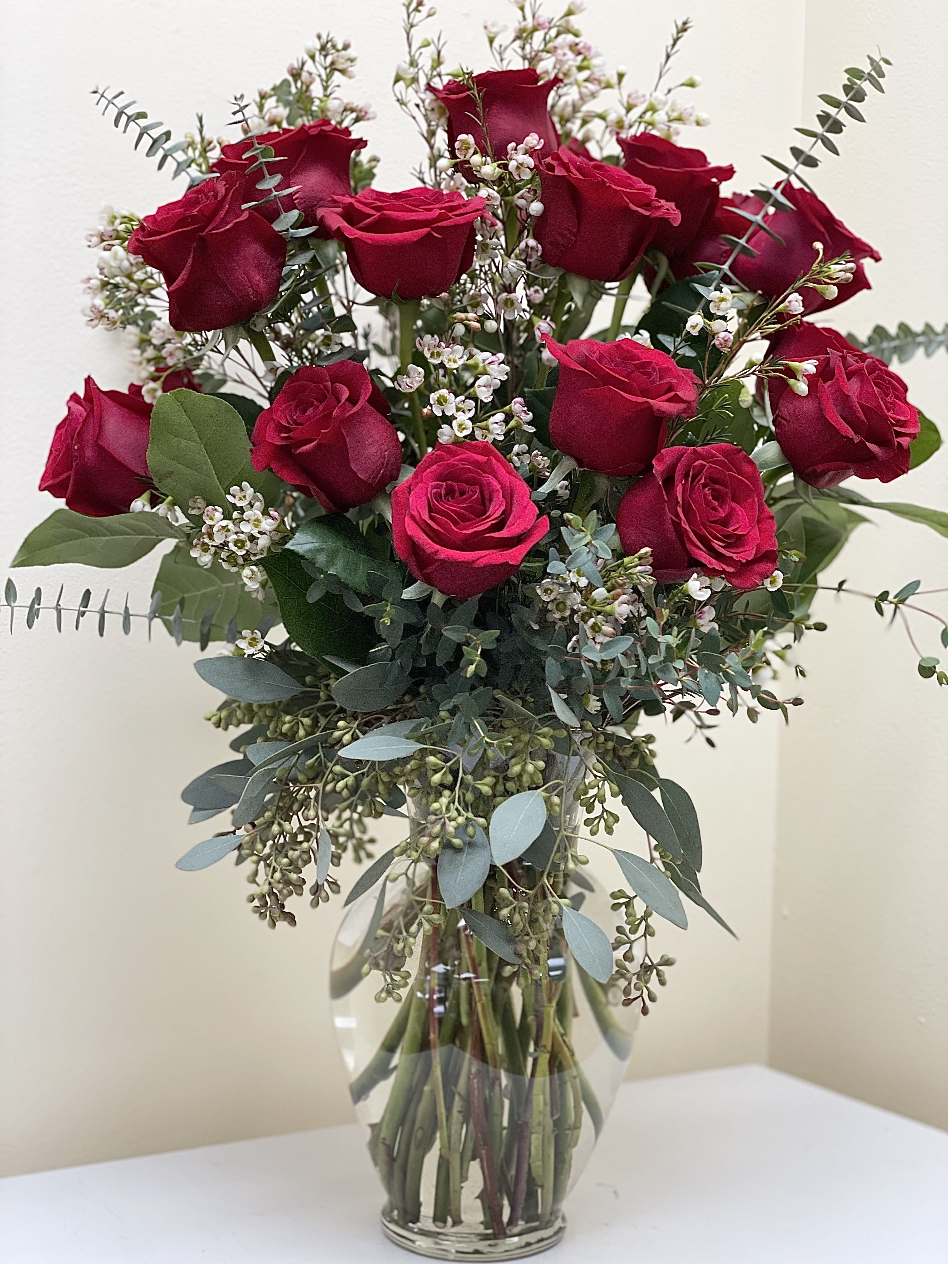 Bouquet of red roses with white filler flowers in a clear glass vase