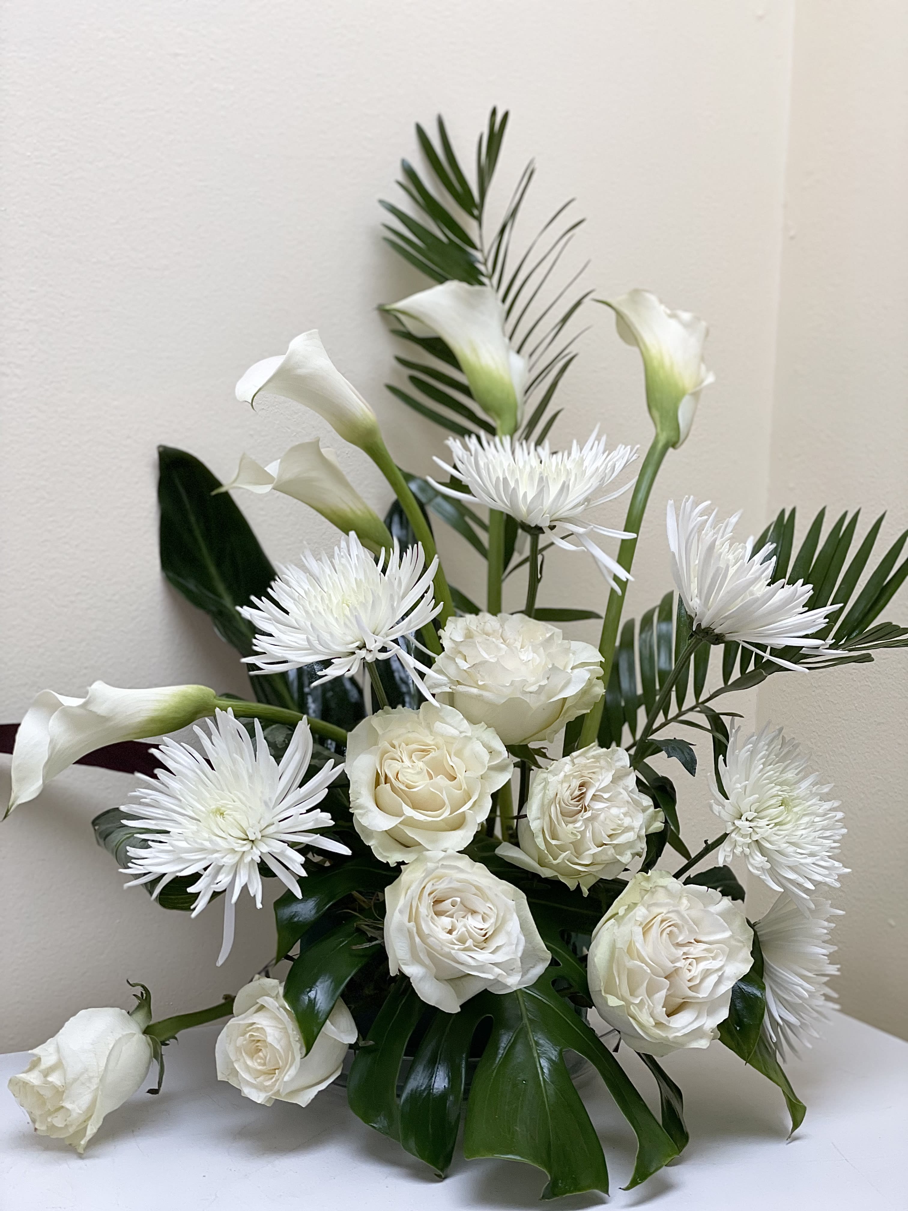 White roses, calla lilies, and spider mums in a low arrangement