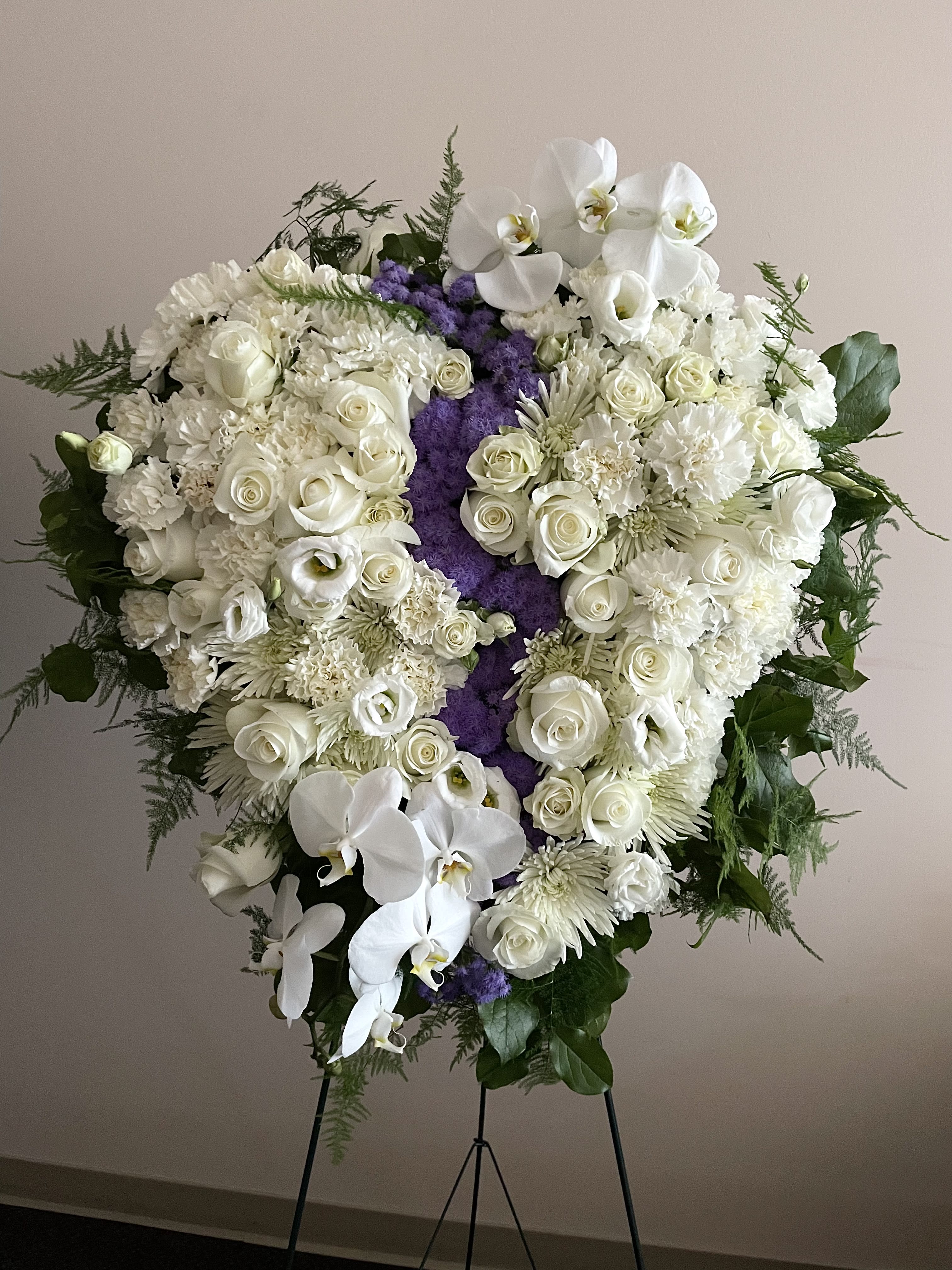 Large white funeral spray with roses and orchids on a stand