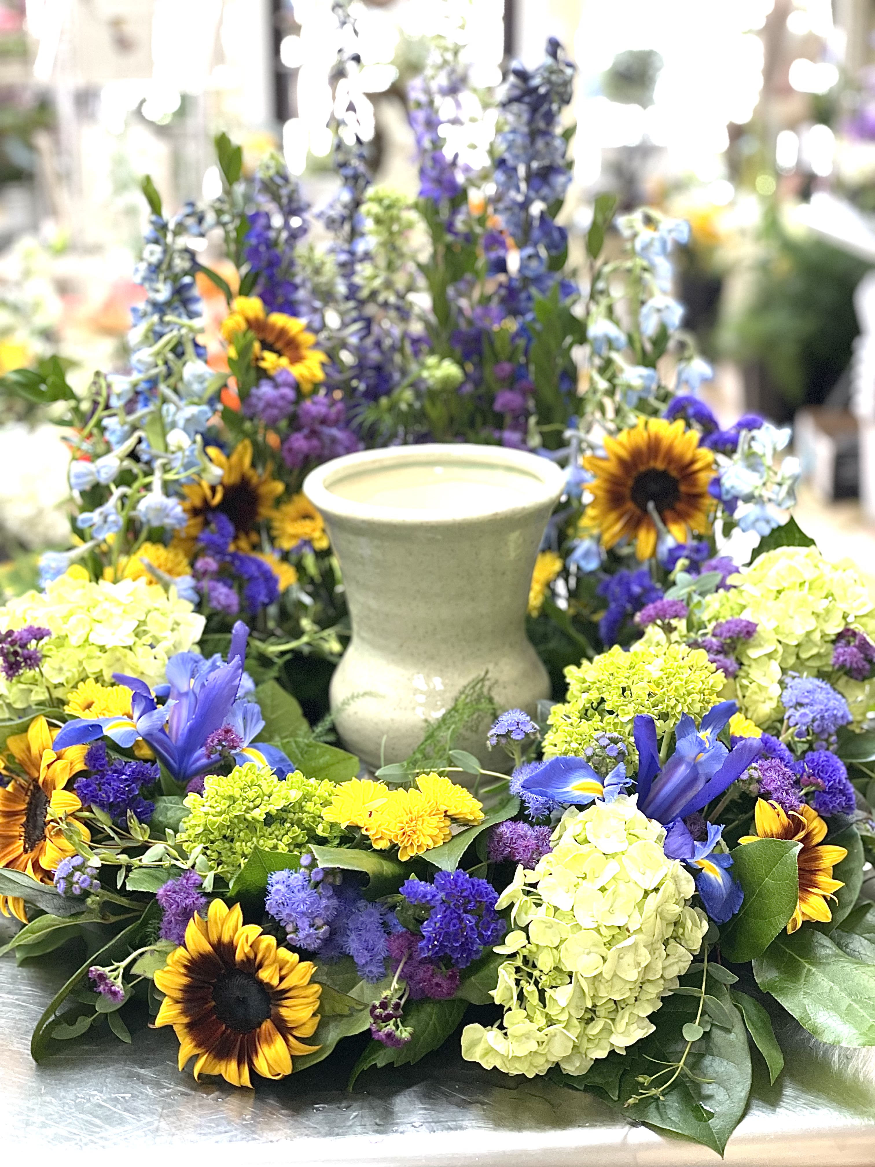 Colorful floral wreath with sunflowers and blue blooms around a candle holder