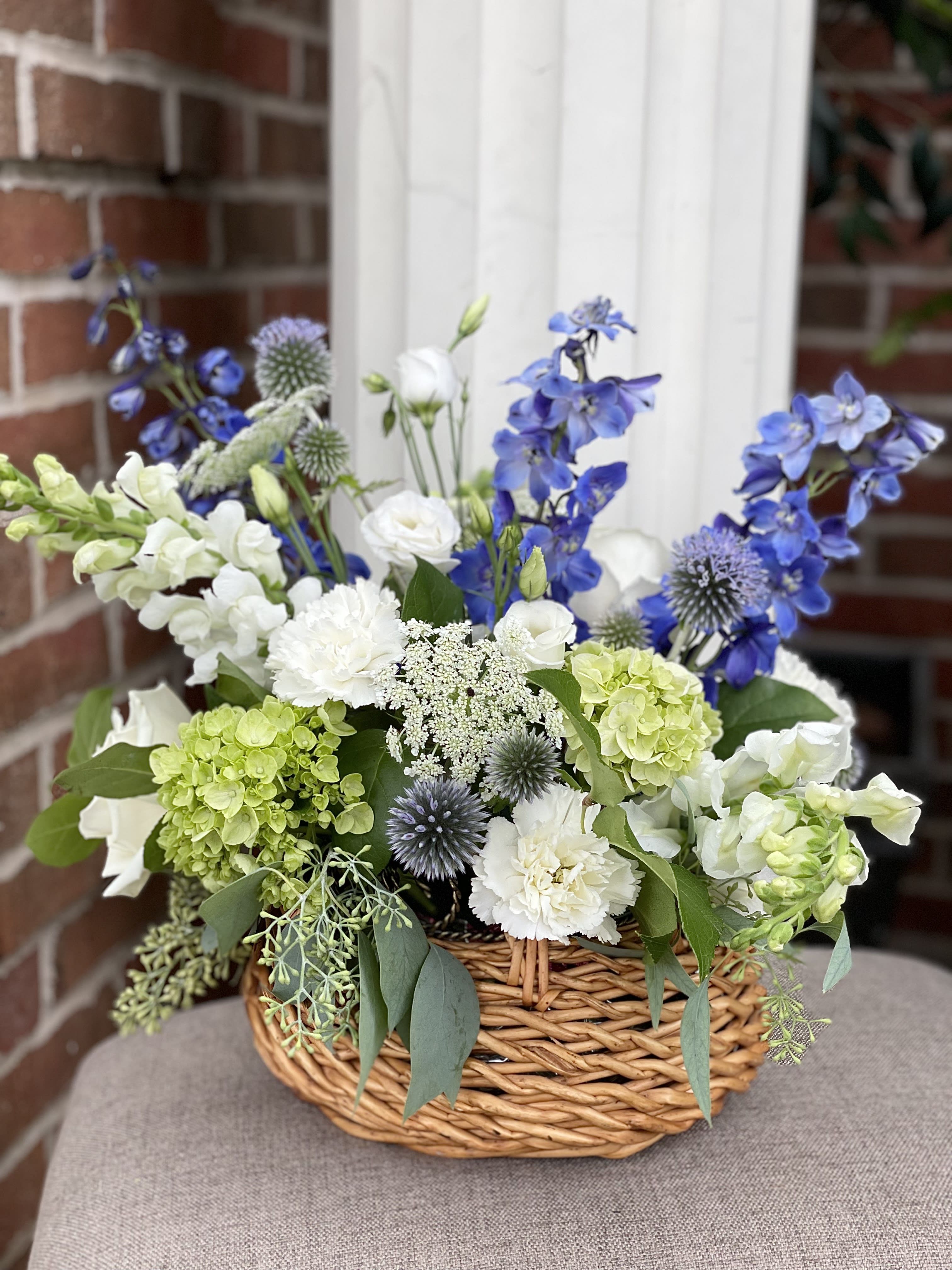 Basket arrangement of blue, white, and green flowers
