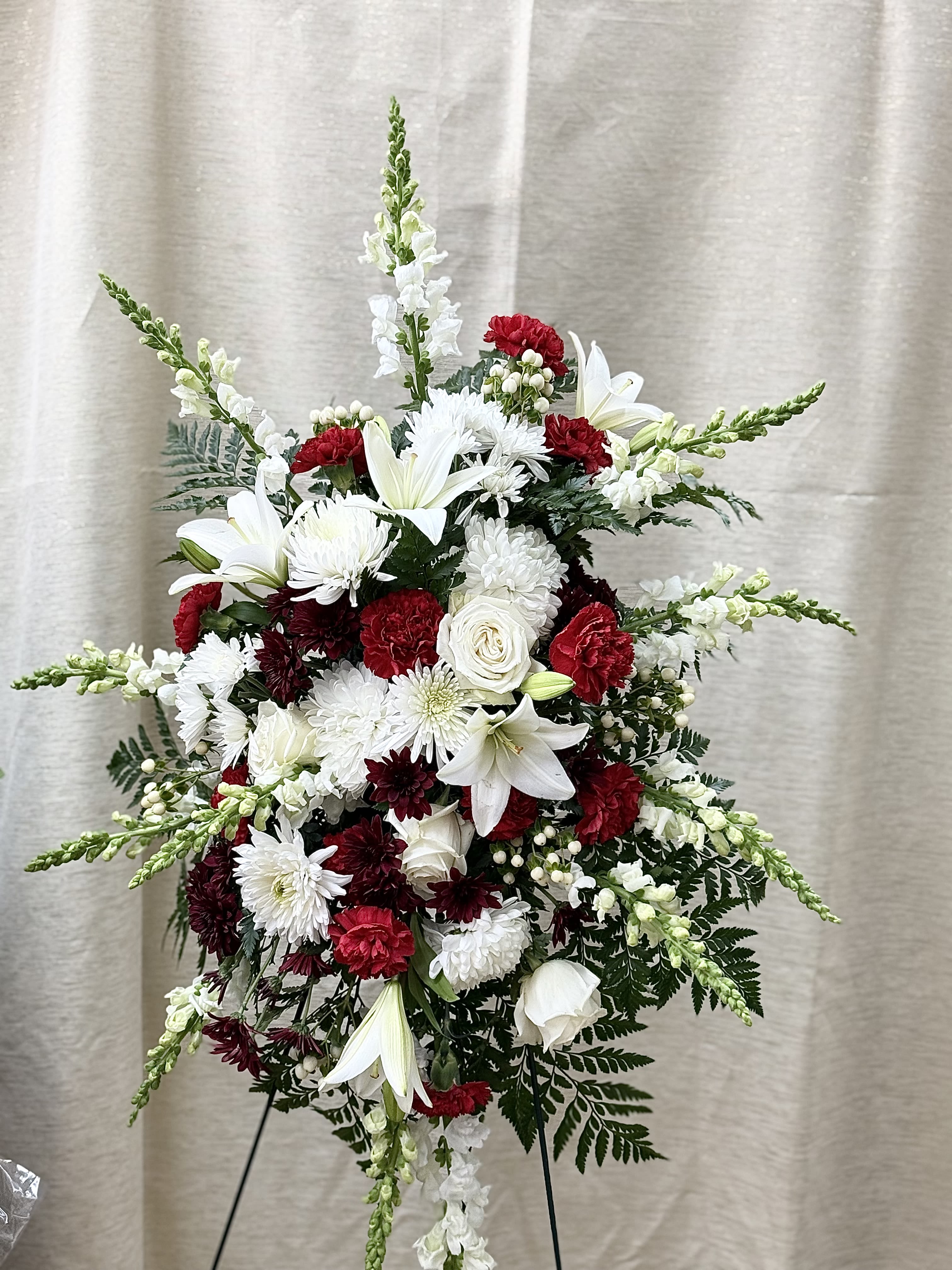 Tall standing floral spray with white lilies, chrysanthemums, and red carnations