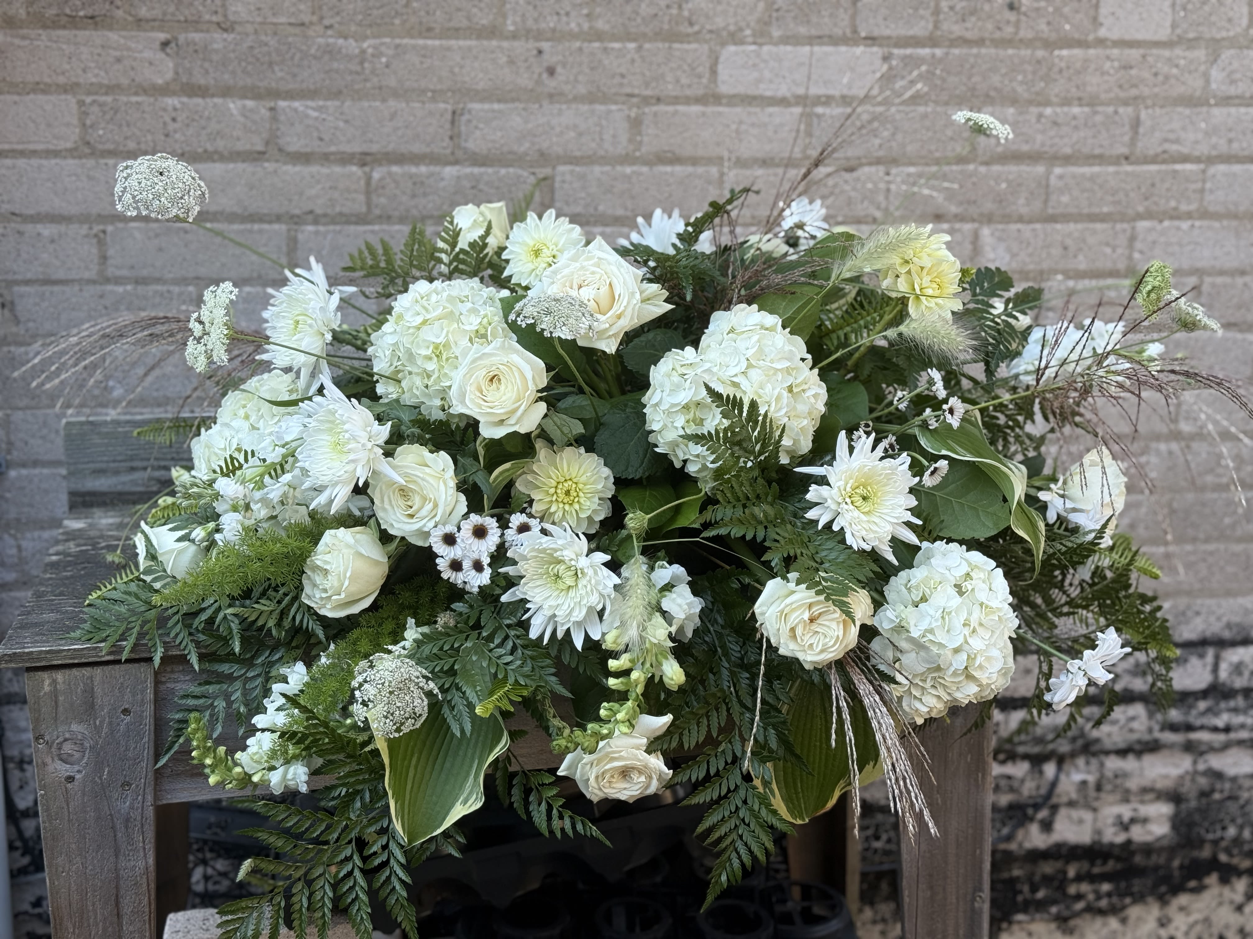 Large white floral arrangement with roses and hydrangeas in a low container
