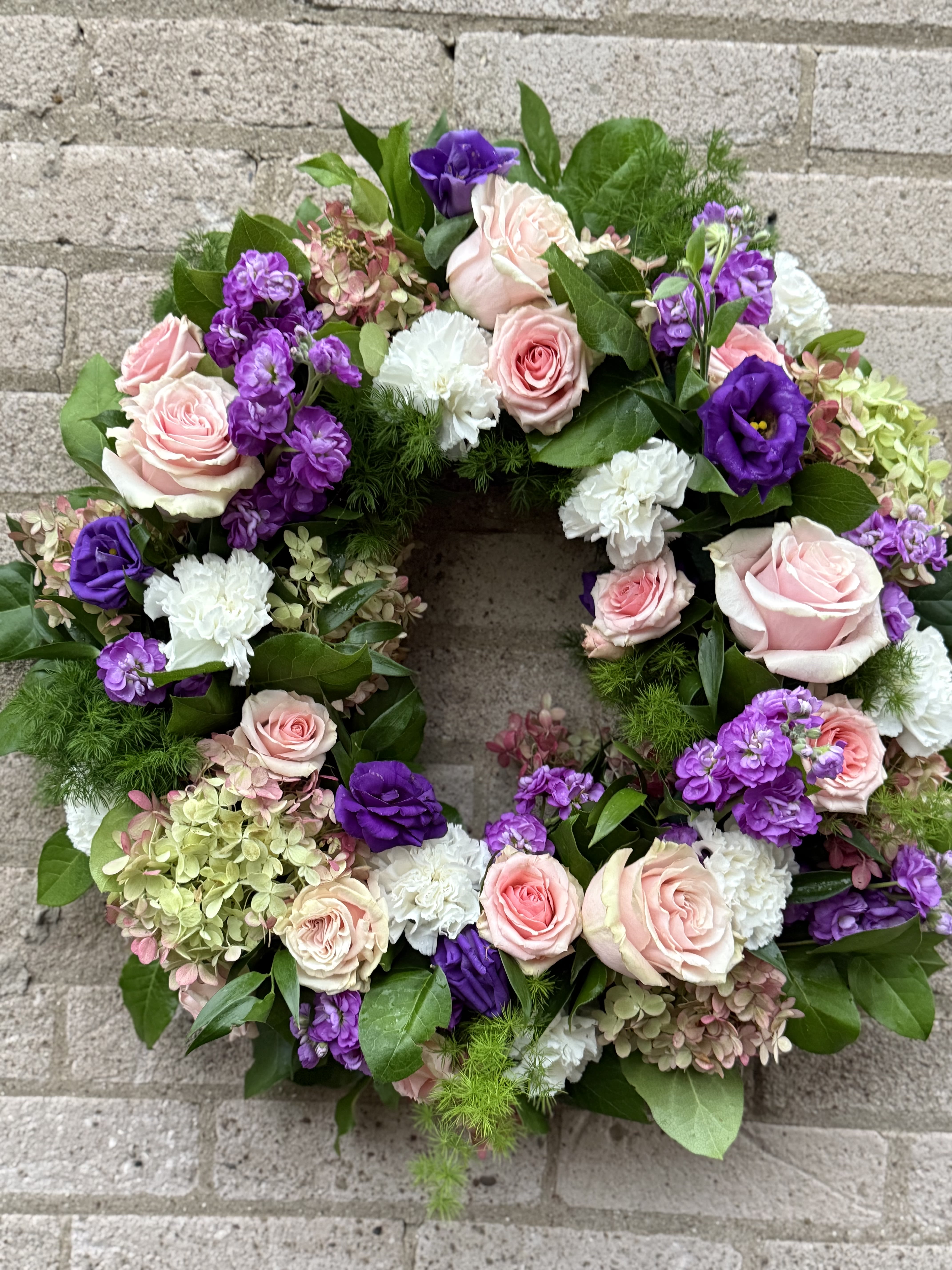 Circular floral wreath with pink, purple, and white blooms