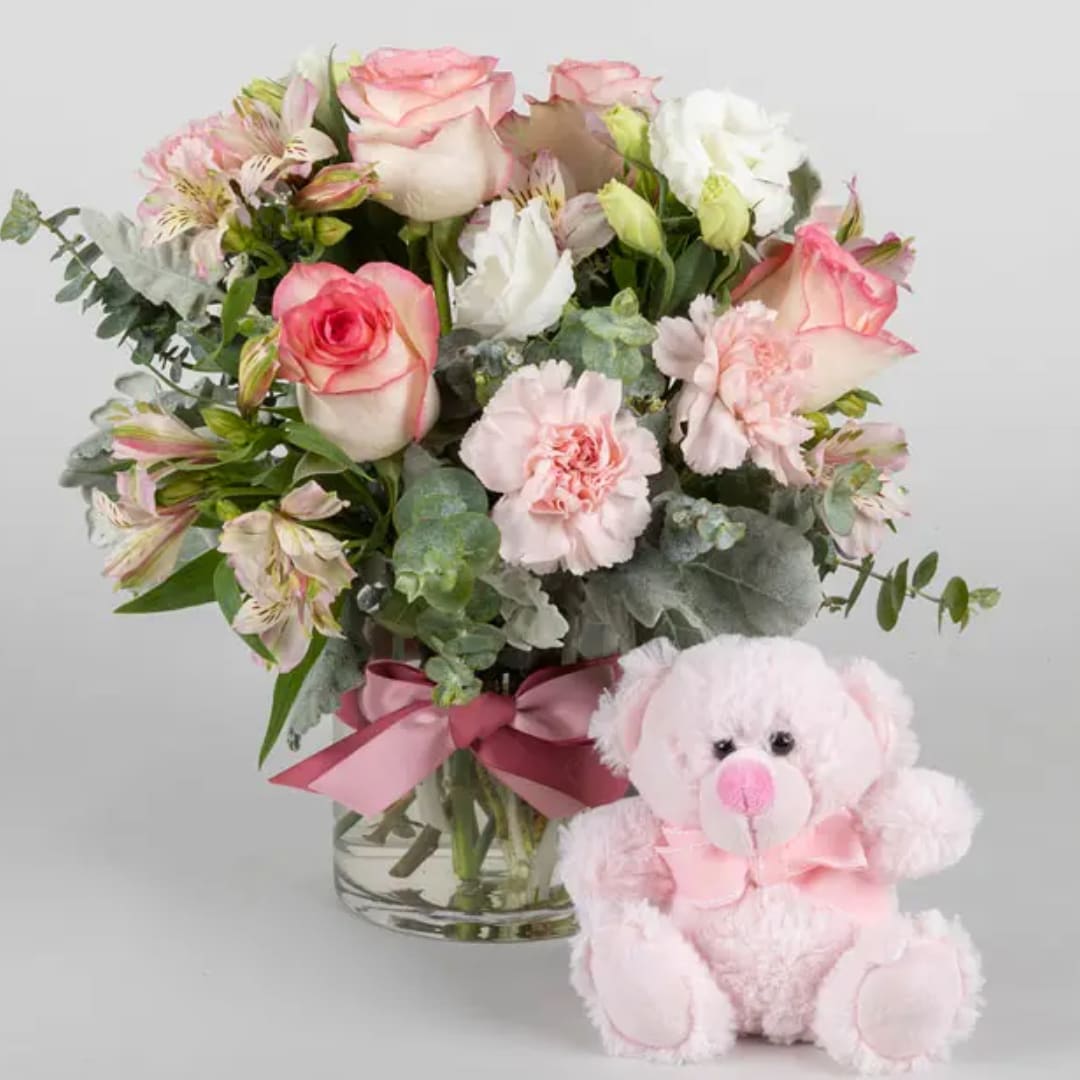 Pink and white bouquet in a glass vase with a pink teddy bear
